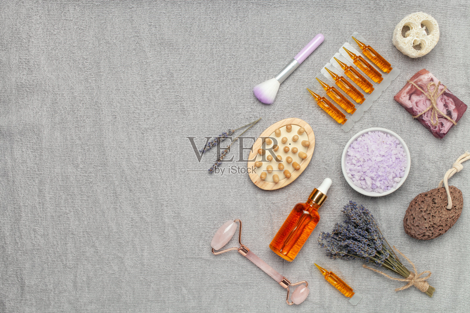 薰衣草化妆品背景。海浴盐、油、石英石面辊、木刷和鲜花。芳香疗法spa。前视图。平的。副本的空间。照片摄影图片