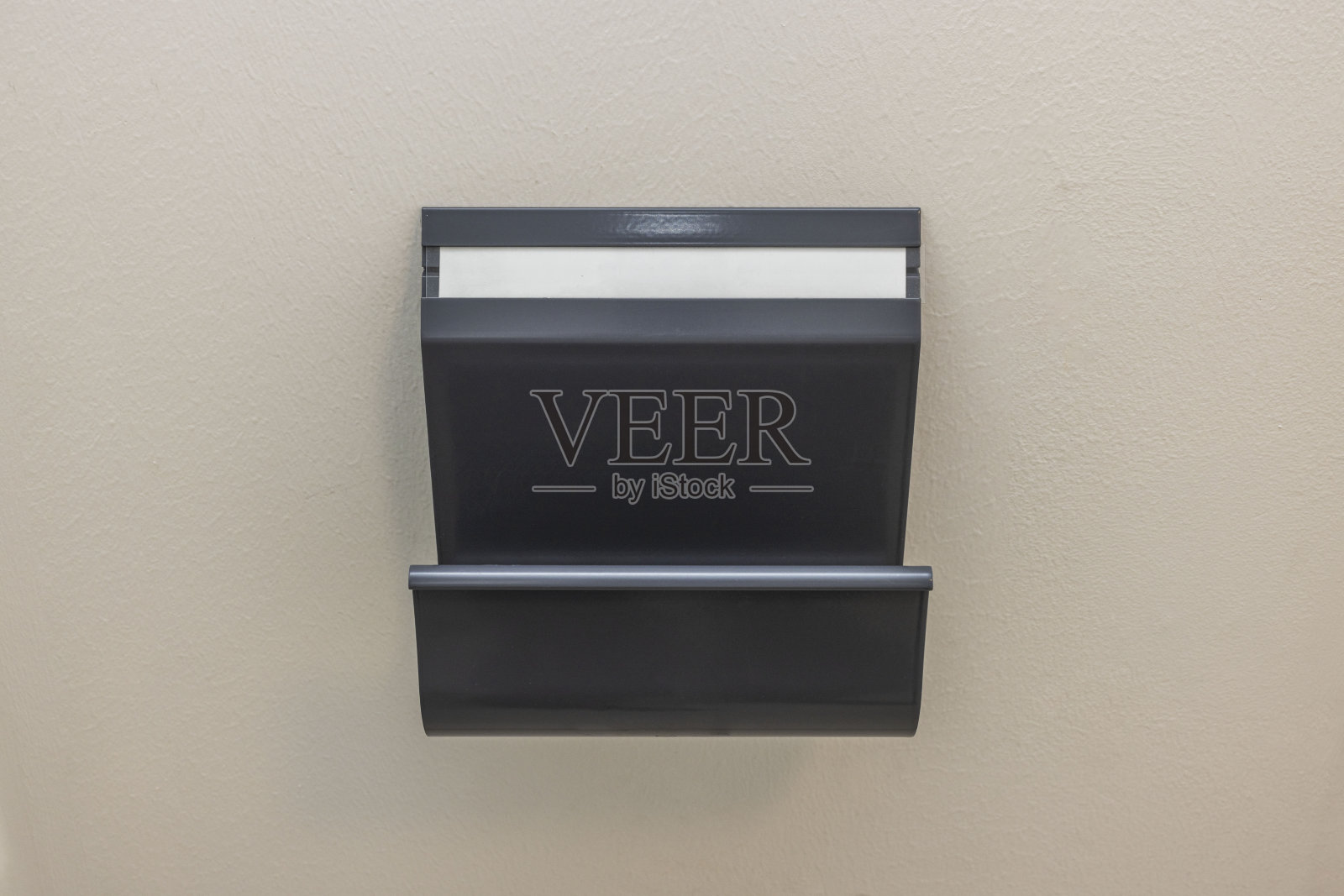 近距离观察深灰色的金属报纸把持在白色墙壁背景孤立。瑞典。照片摄影图片