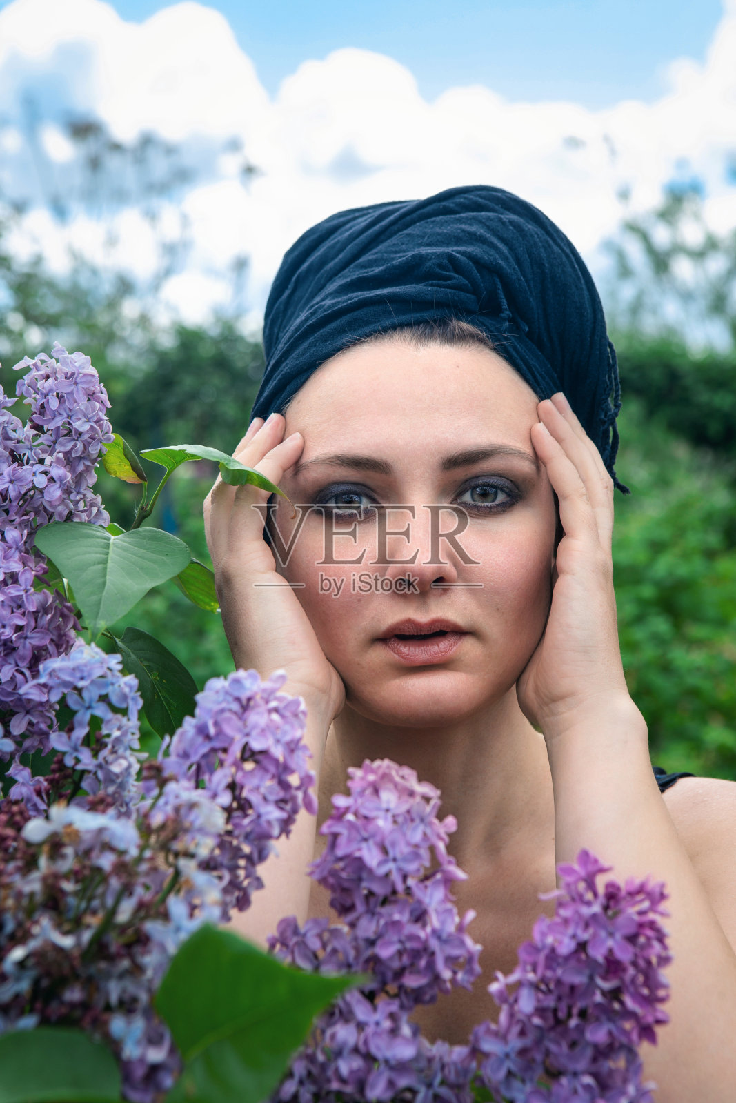 年轻女子的肖像与头巾在花园里紫丁香照片摄影图片