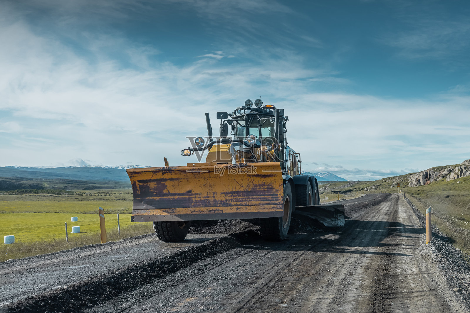 在冰岛对碎石道路进行分级或勾画的分级员。对没有铺沥青的冰岛典型道路进行例行维护。冰岛阳光明媚。照片摄影图片