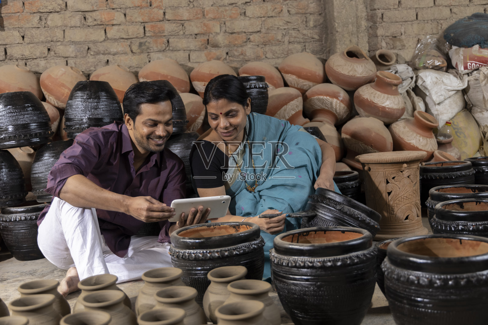 夫妇使用数码平板，而油漆罐在车间照片摄影图片