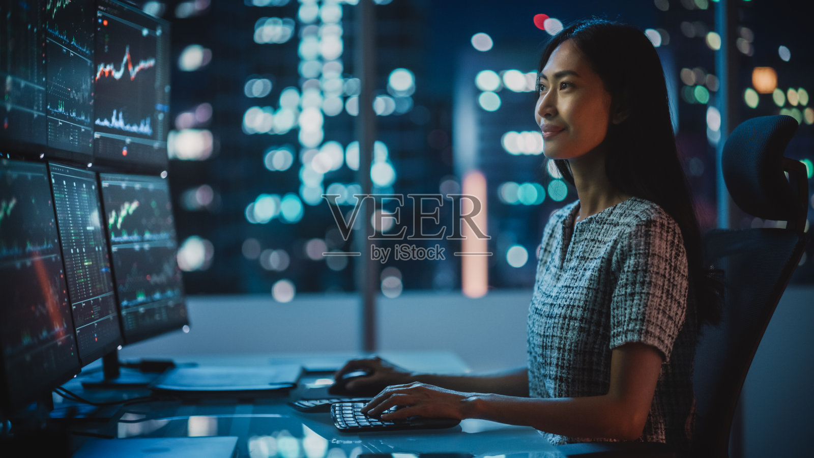 一名金融分析师在计算机上工作的肖像与多显示器工作站与实时股票，商品和交易所市场图表。在投资经纪人机构工作的女商人。照片摄影图片