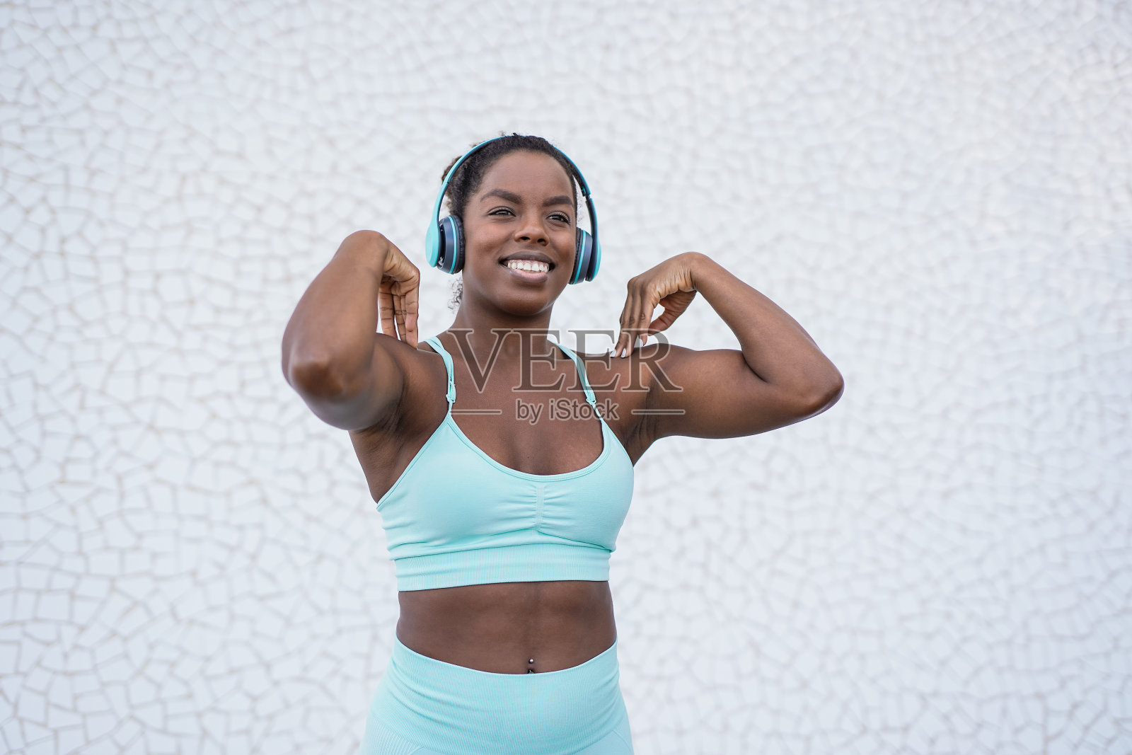 年轻的非洲妇女一边用无线耳机听音乐一边做伸展运动照片摄影图片