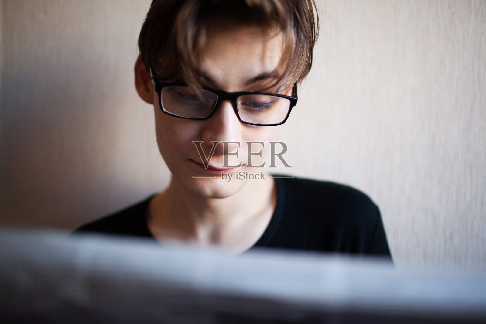 一个年轻人正在看报纸，脸上带着感情照片摄影图片