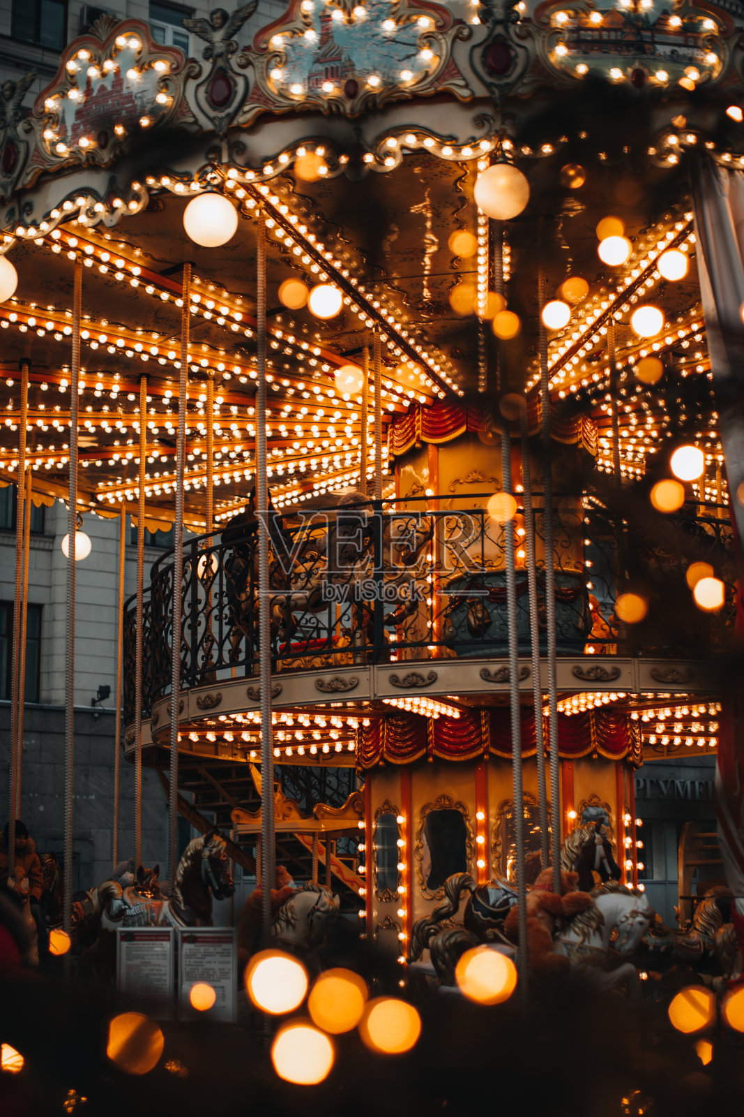 闪亮的金色儿童魔法旋转木马，木马在夜晚的灯光下旋转。照片摄影图片