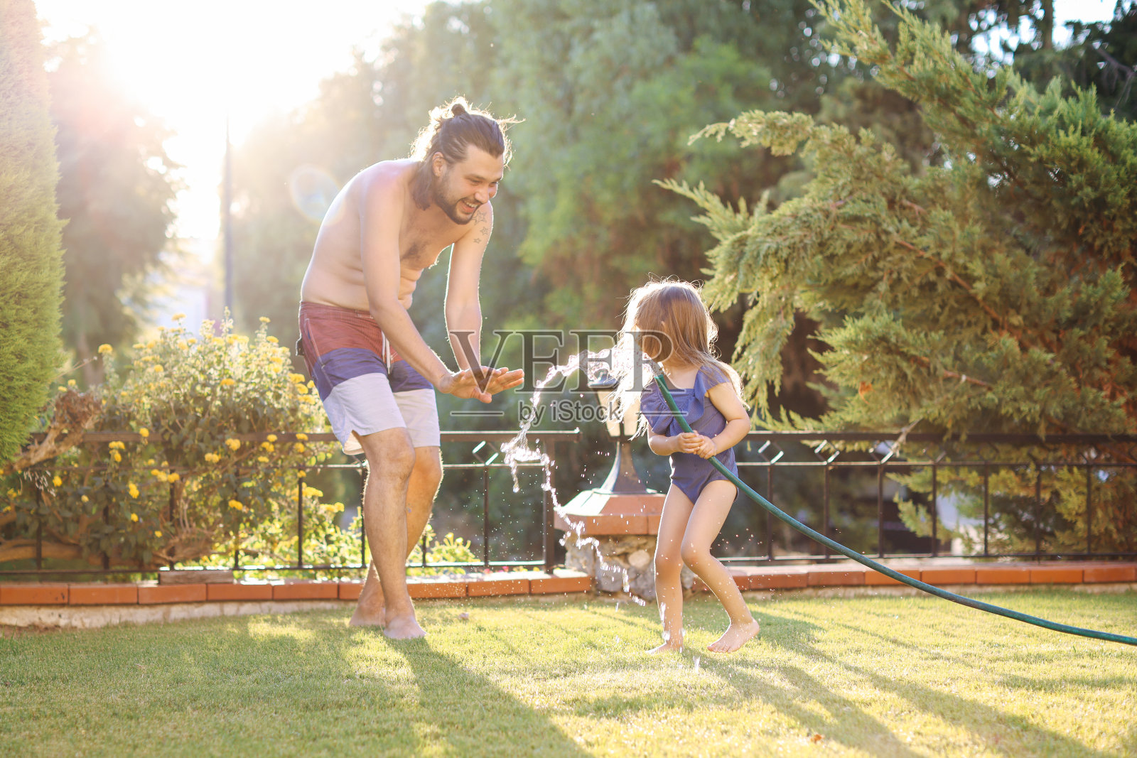 一个幸福的家庭通过洒水喷头照片摄影图片