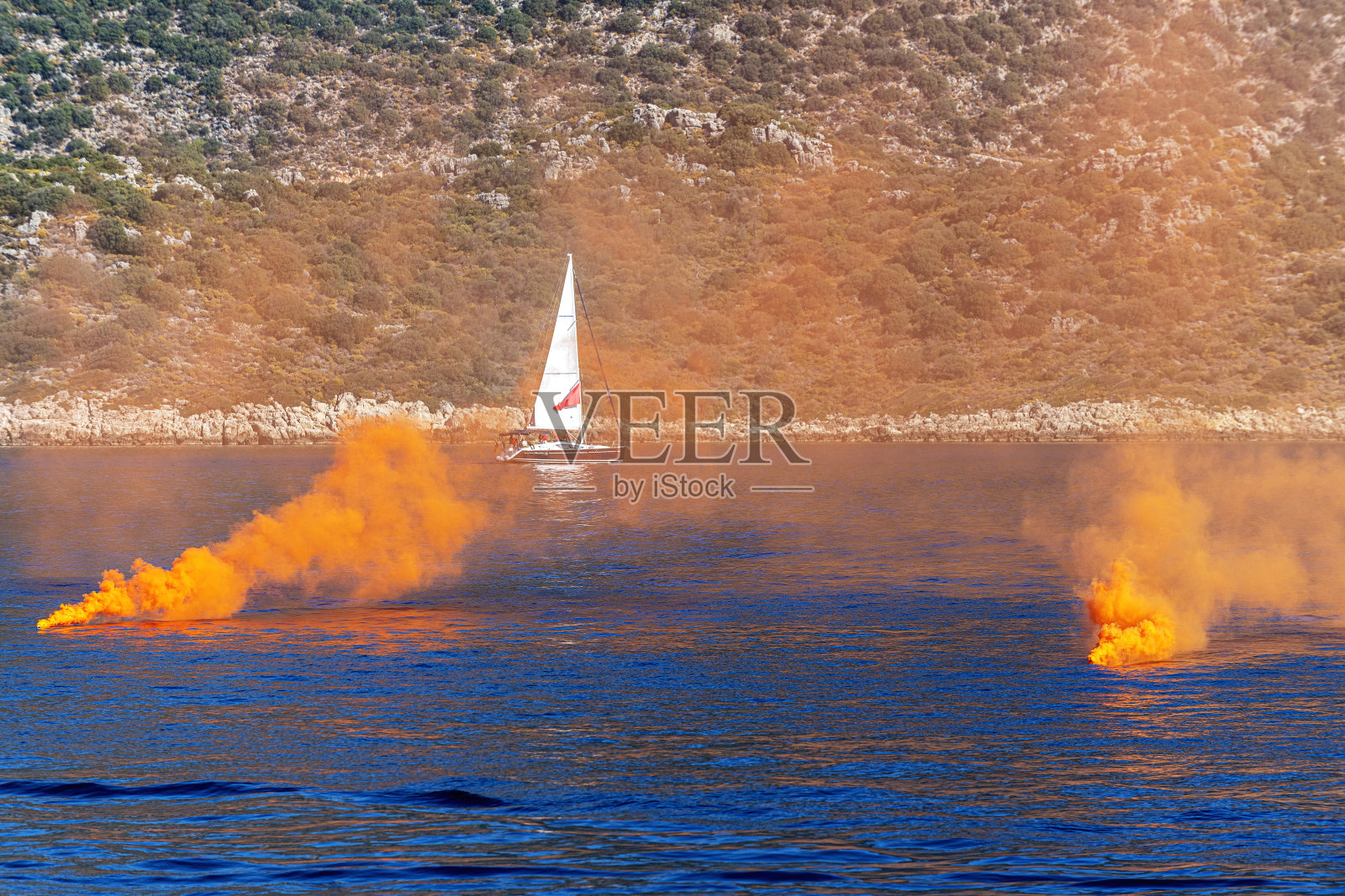 橙色烟雾弹与帆船。遇险信号照片摄影图片