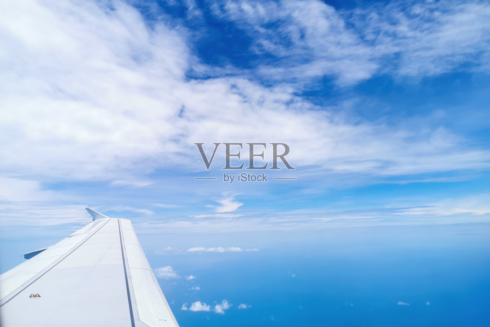 飞机飞行。一架飞机的机翼在金色蓬松的云朵上方飞行，轻柔地在天空中移动，阳光透过云朵散发出美丽的光芒。照片摄影图片