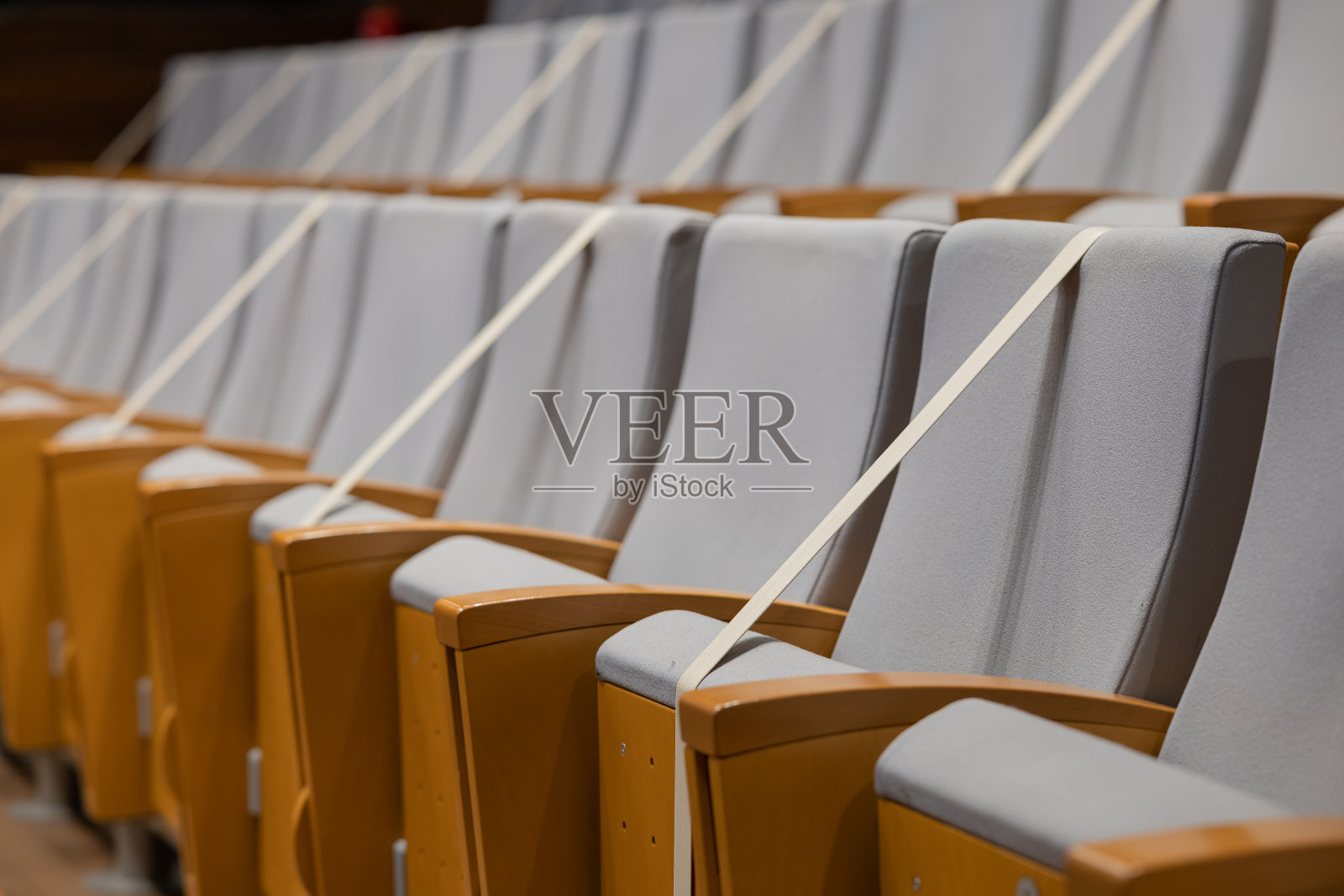 为了预防冠状病毒covid - 19疾病，在剧院堵住了单座。在剧院或电影院等场合，用胶带把座位粘上，以保持社交距离。照片摄影图片