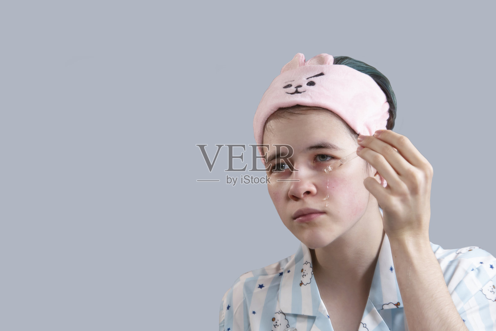 一个年轻的女孩在她的脸上涂抹一种美容血清。护肤，健康生活。使用复制空间隔离。照片摄影图片