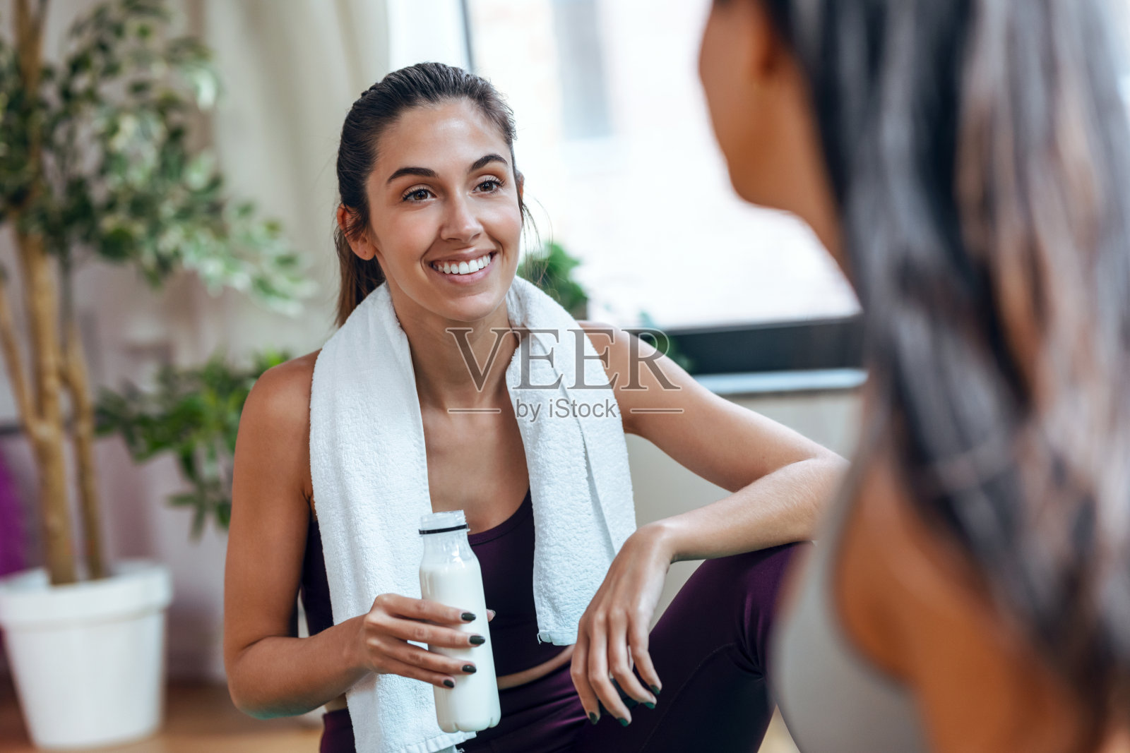 两个运动的年轻女子在家里的地板上通过笔记本电脑在线上体育课。照片摄影图片