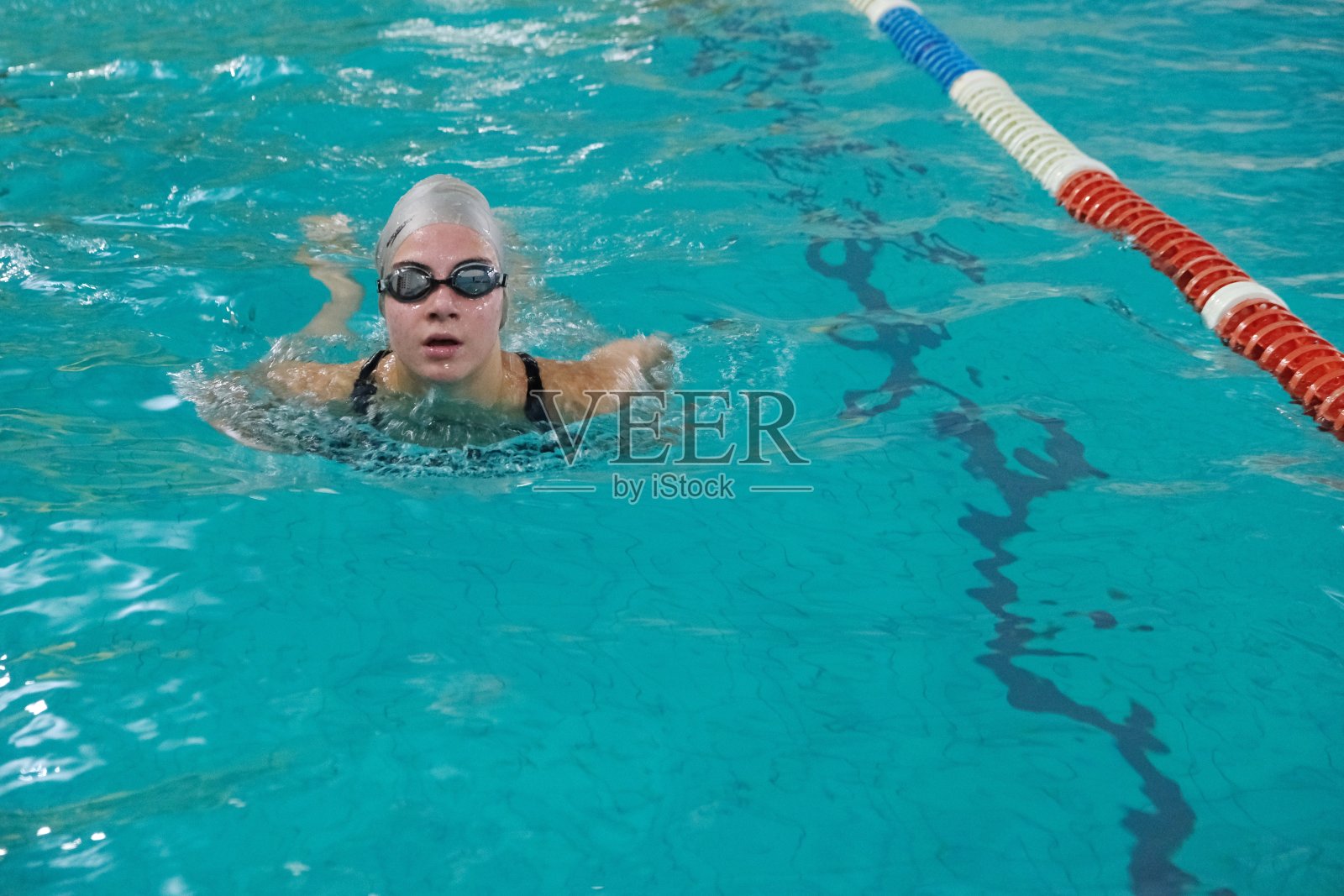 一个女孩在游泳池里游泳。照片摄影图片