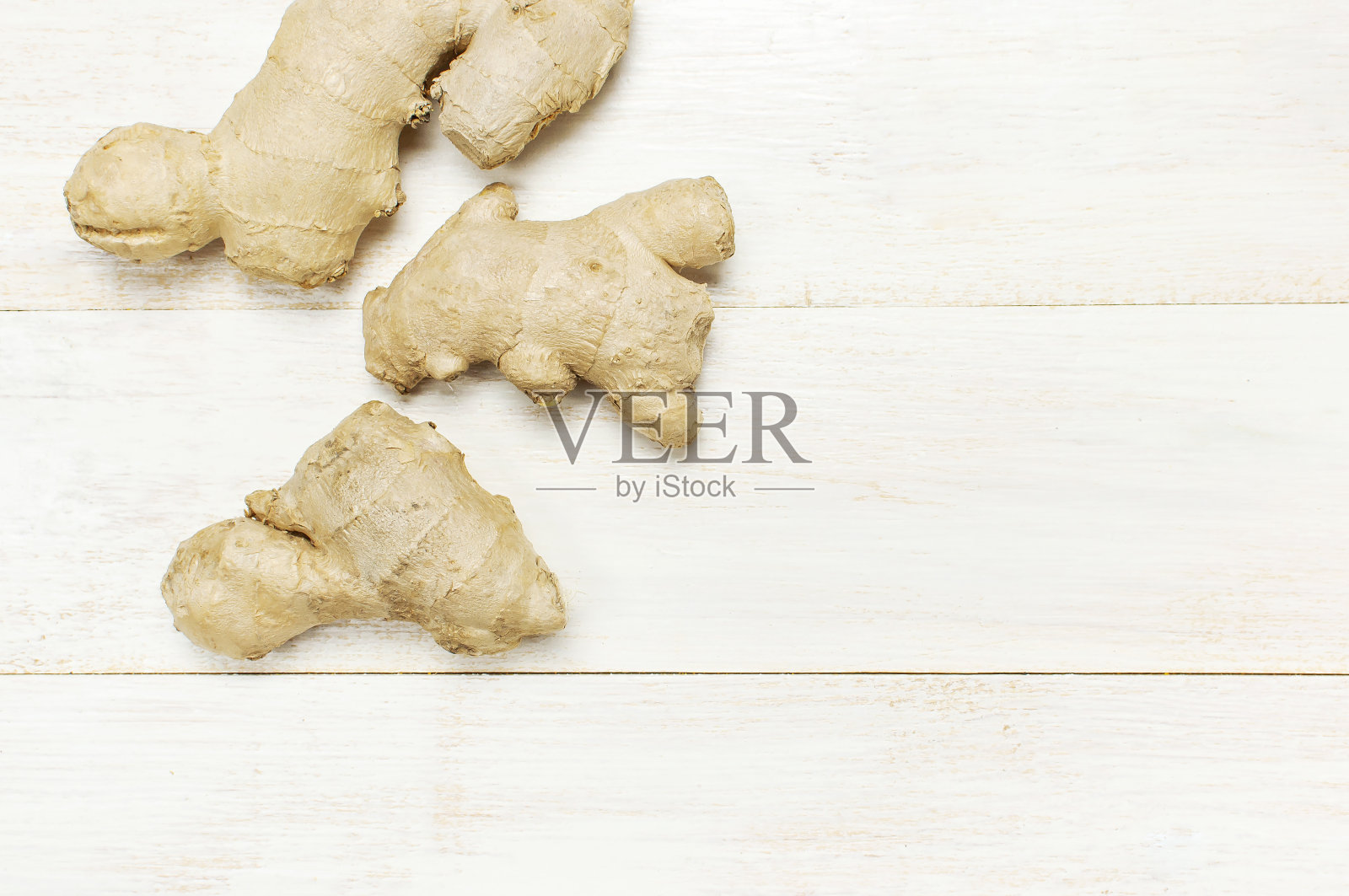 新鲜生姜根在白色木制背景顶视图与复制空间。极简风格，调味料，香料，茶的配料。理念健康食品，医药，提高免疫力照片摄影图片
