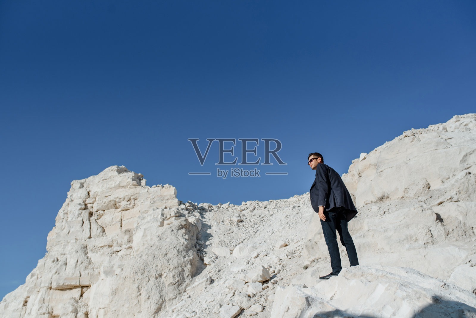 一个穿着古装、夹克、领带、戴着眼镜的男人在山上摆姿势。照片摄影图片