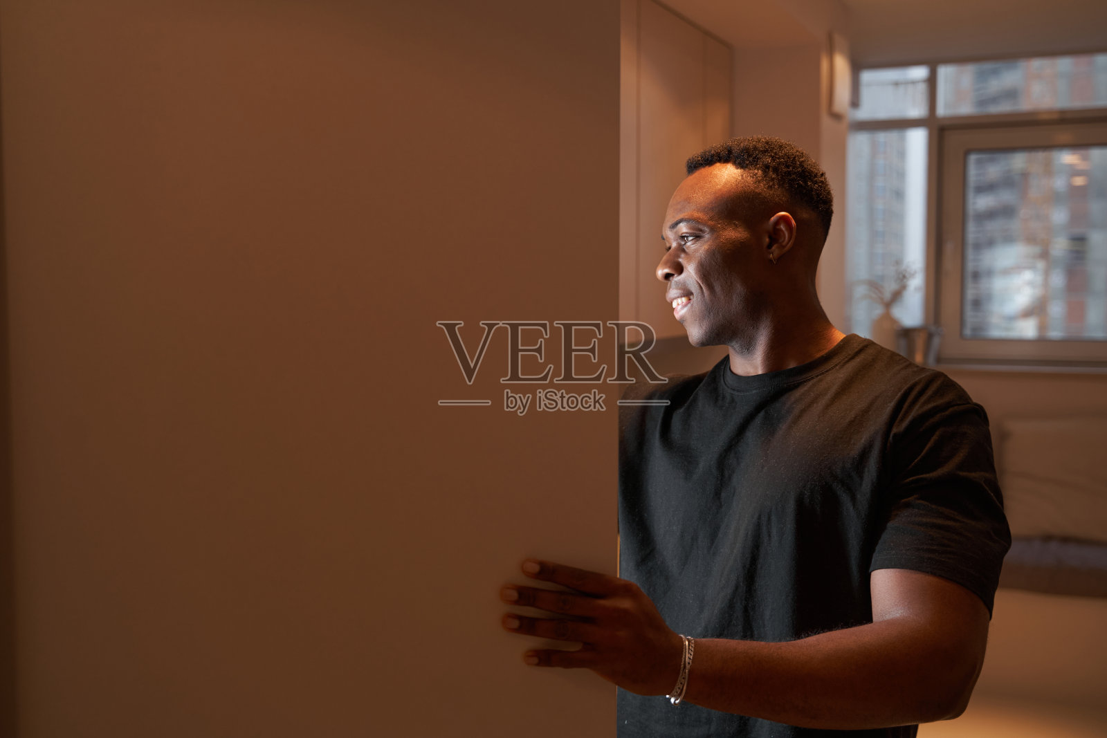 微笑的男人打开厨房橱柜，往里面看照片摄影图片