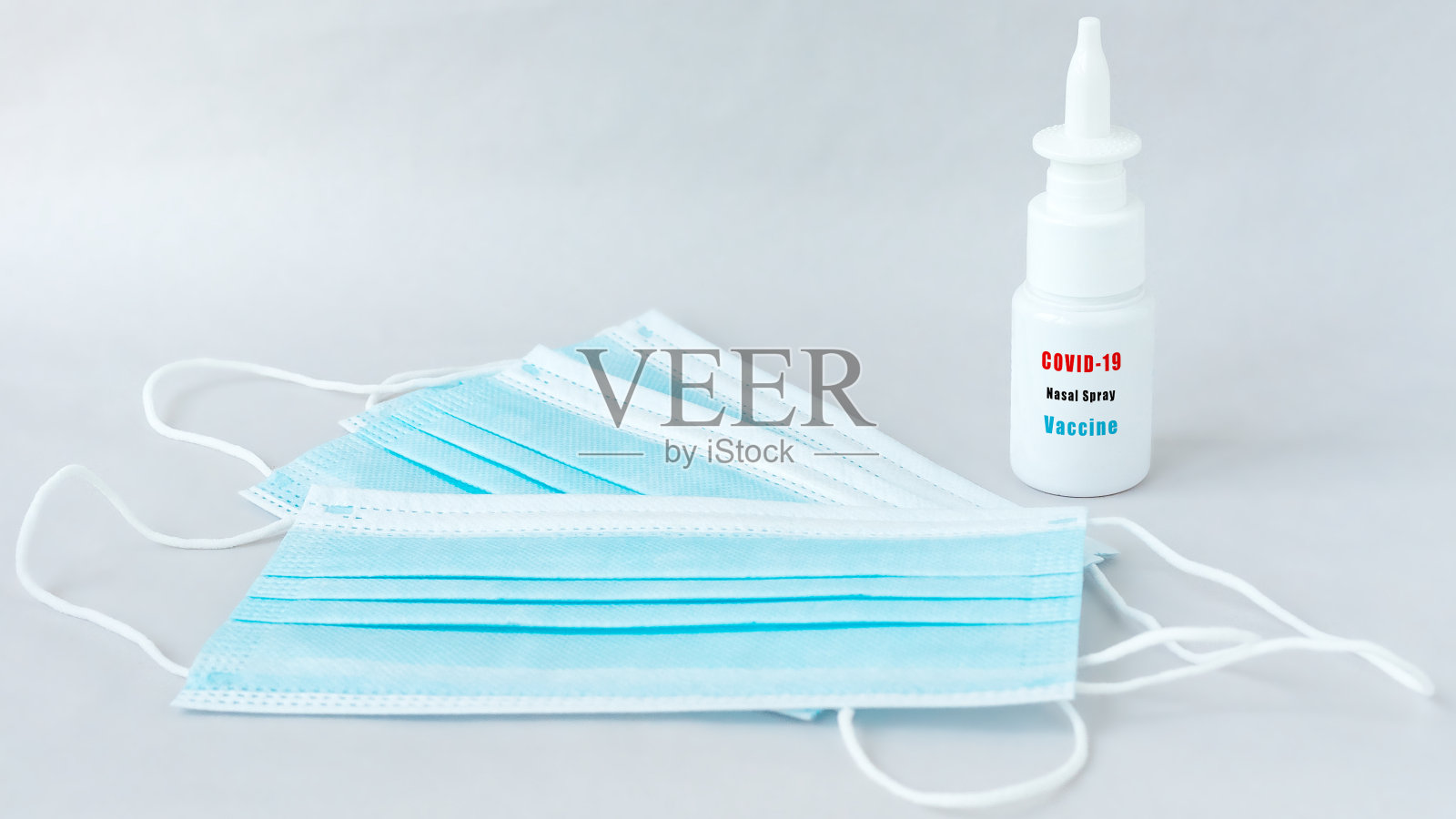 一瓶抗covid-19鼻喷雾和外科口罩。照片摄影图片