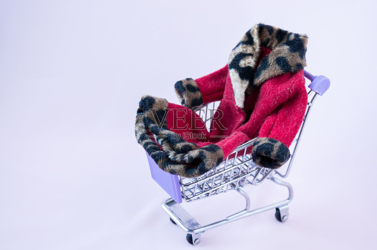 铁购物车与红色外套在粉红色的背景照片摄影图片