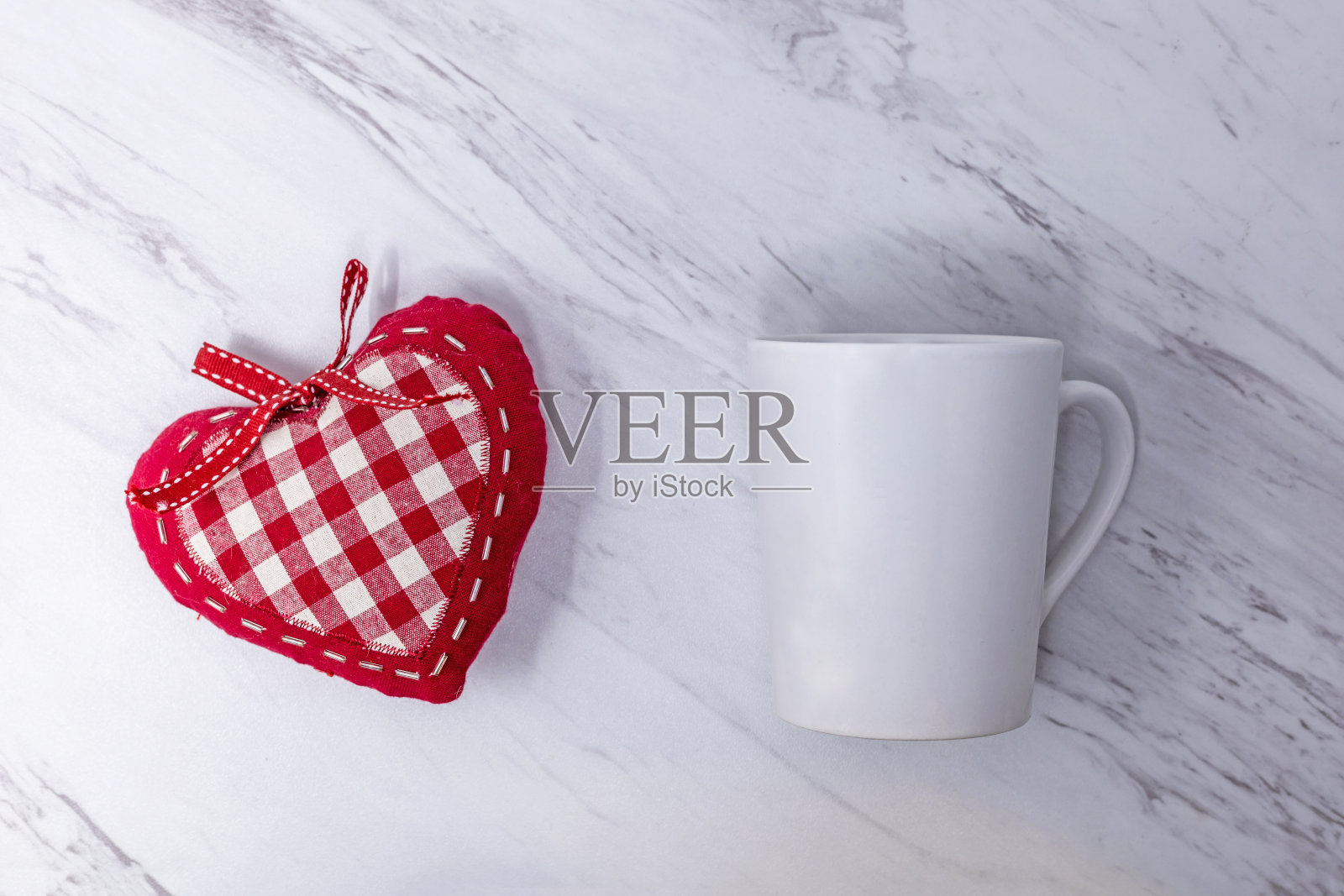 白色杯子模型在白色大理石背景与红色长毛绒平躺为情人节，复制空间，添加您的文本，标志，艺术品照片摄影图片