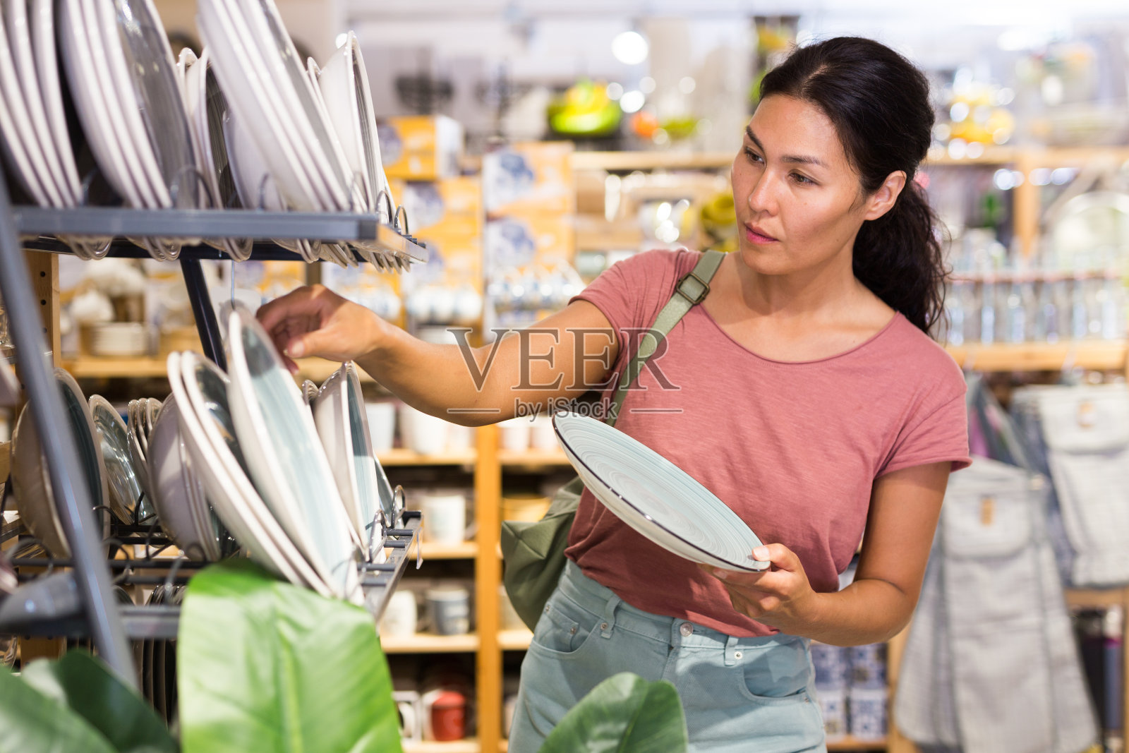 积极的女性买家在餐具店挑选新盘子照片摄影图片