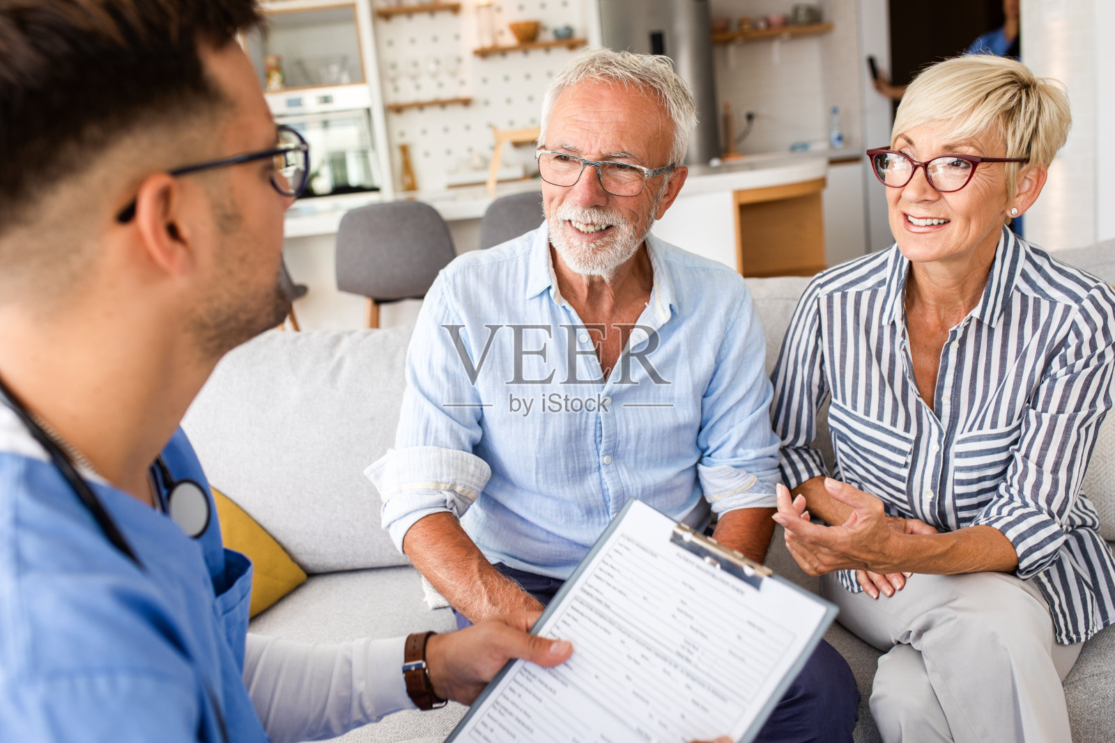 男护士在家访时与老年病人交谈。照片摄影图片