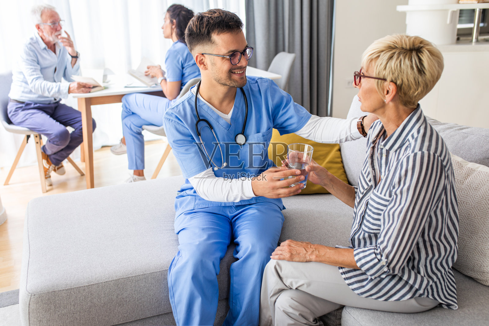 男护士在家访时与老年病人交谈。照片摄影图片