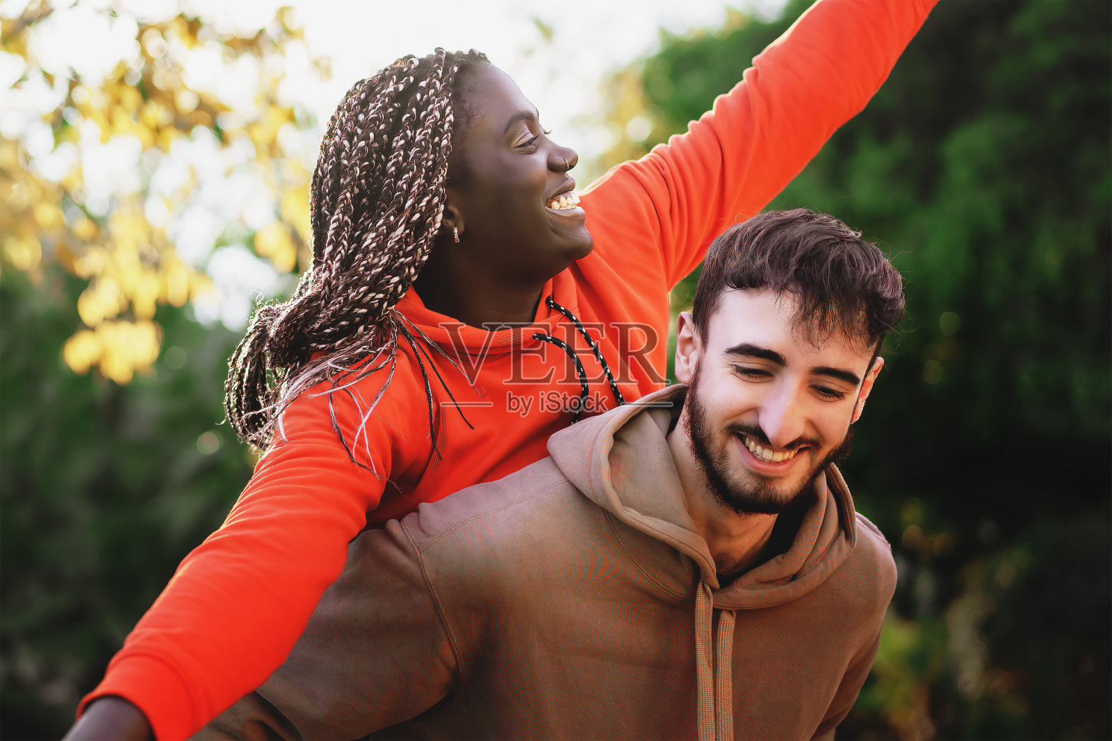 喜气洋洋的z世代混血儿女人背着拥抱微笑的白人男友男人的肖像照片摄影图片