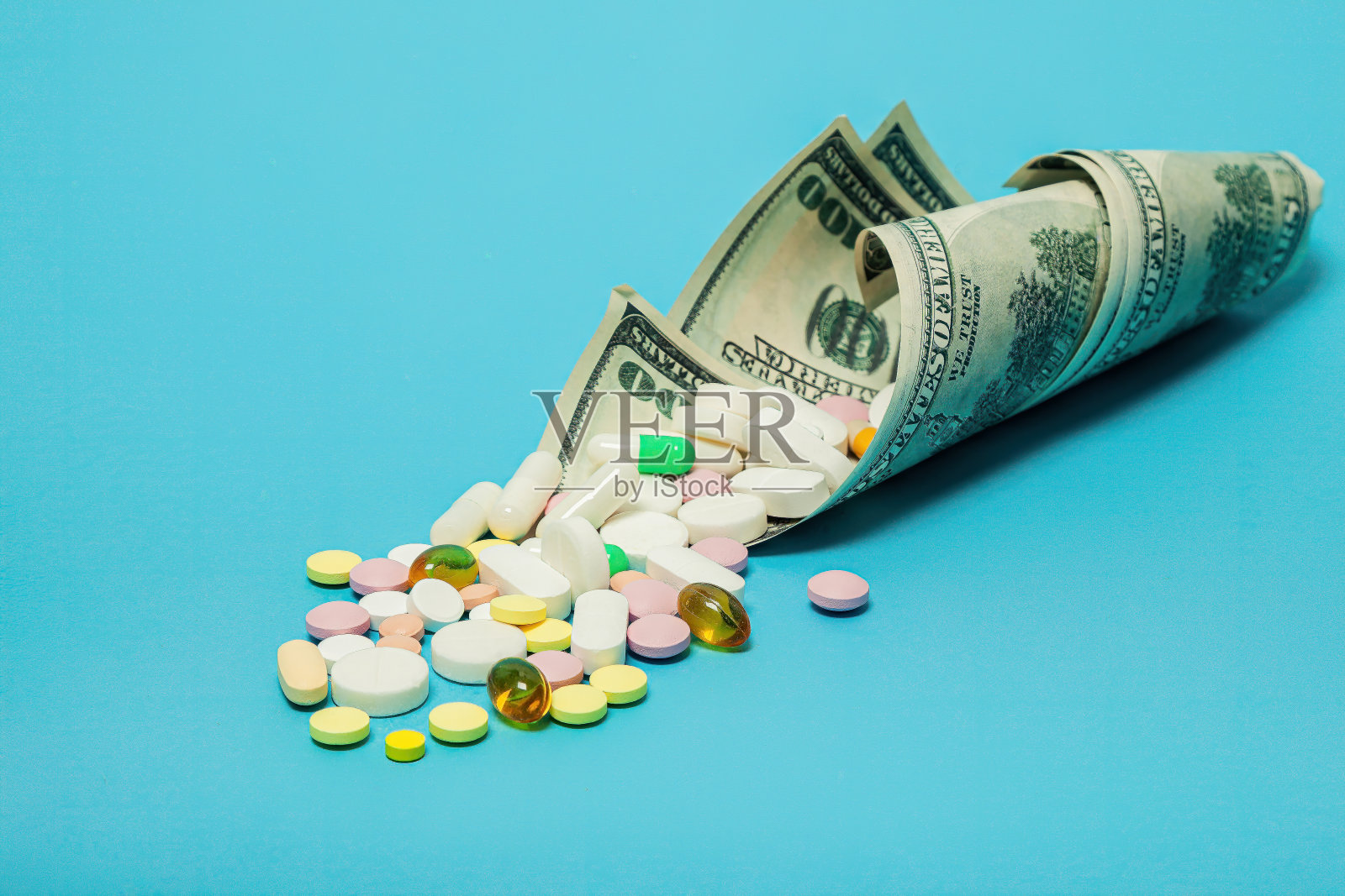 蓝色背景上不同颜色的钱和药丸。医疗费用的上涨。医疗保险概念，保险高，药费高，药费高。照片摄影图片