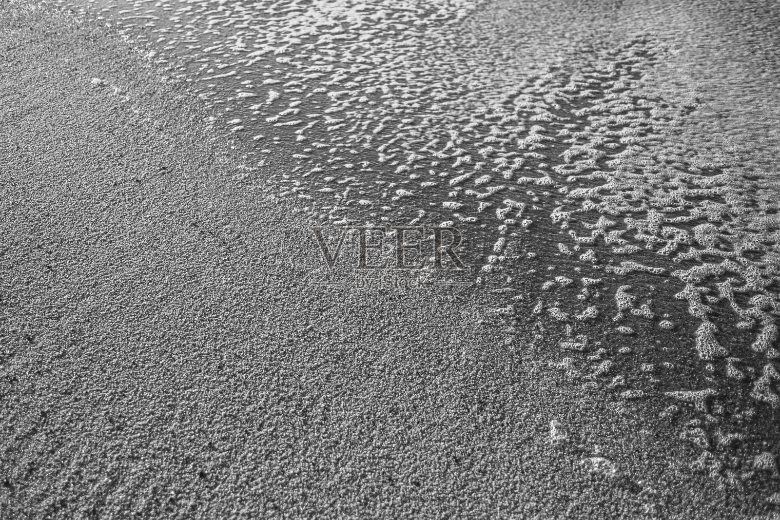 海滩上的沙子和泡沫是大西洋葡萄牙海岸的浪花。黑白照片。照片摄影图片