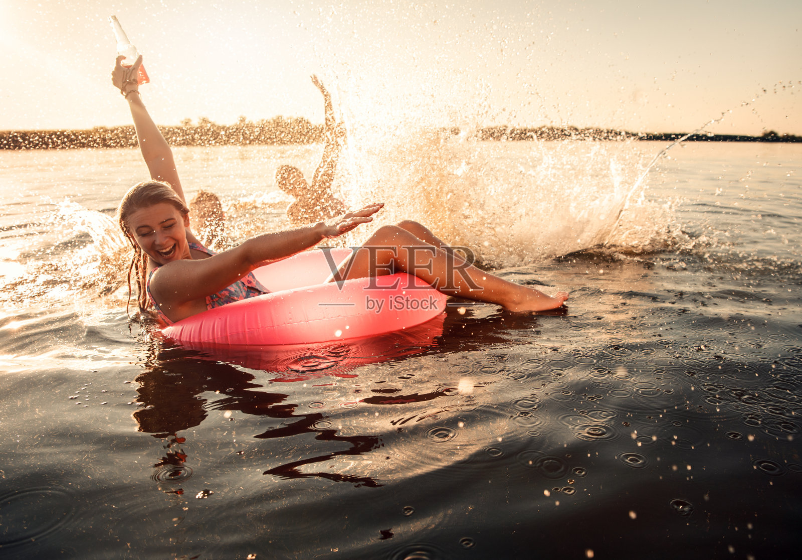 年轻的朋友们在湖边享受夏日游泳的乐趣。照片摄影图片
