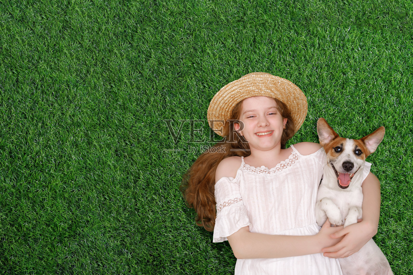 可爱的女孩和小狗拥抱，躺在绿色的草地上照片摄影图片