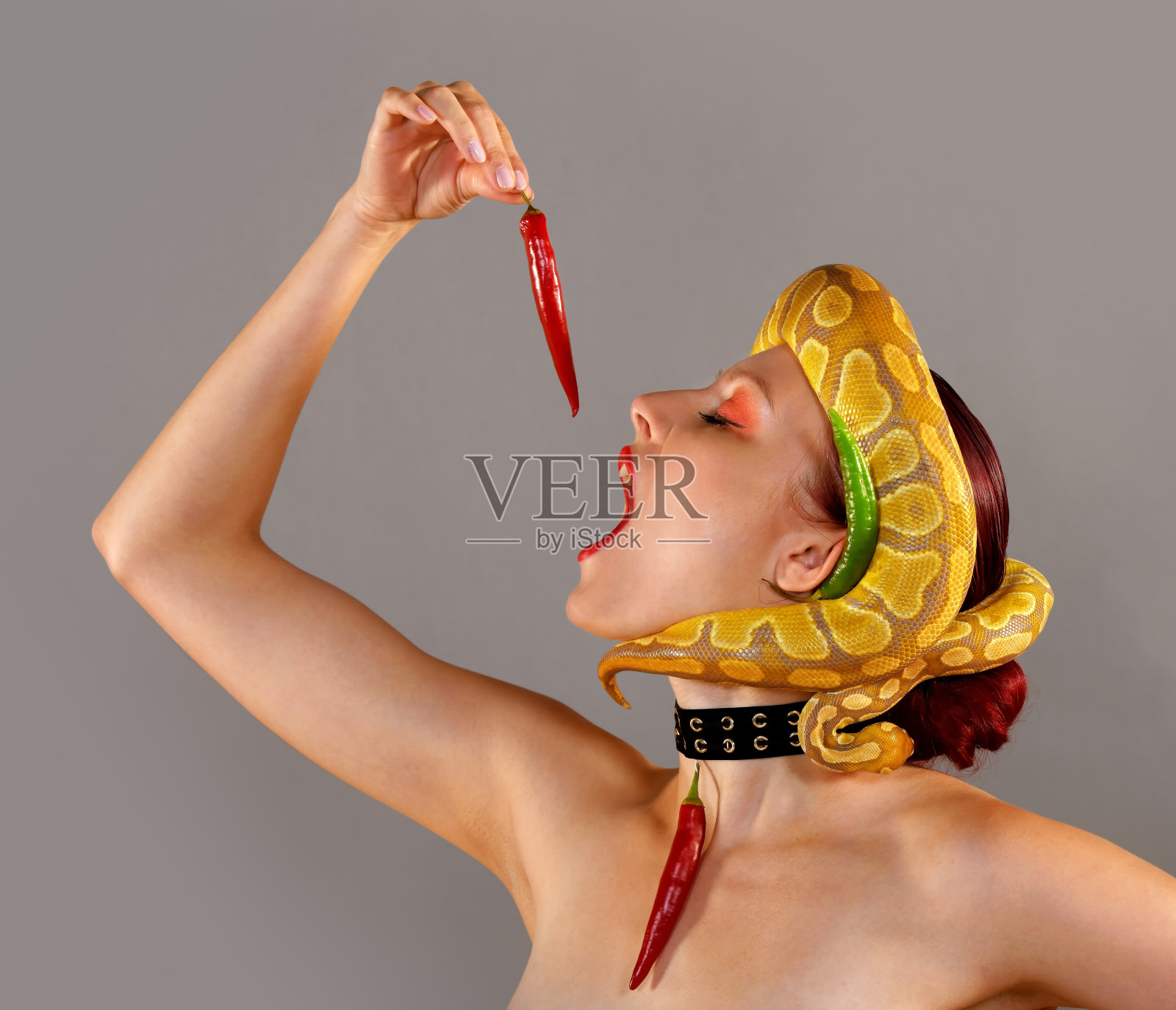 头上有蛇的美女在吃辣椒照片摄影图片
