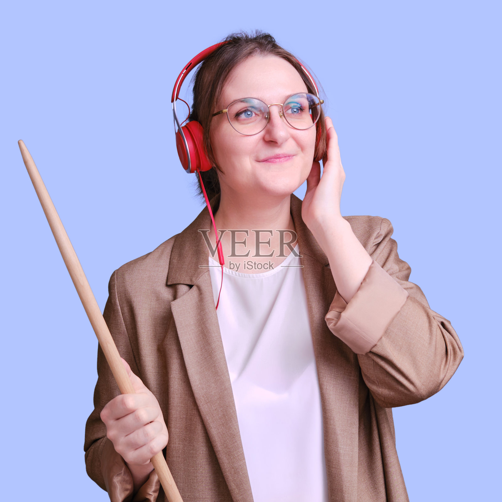 快乐的女教师听音乐，戴着红色耳机，蓝色背景，复印空间照片摄影图片