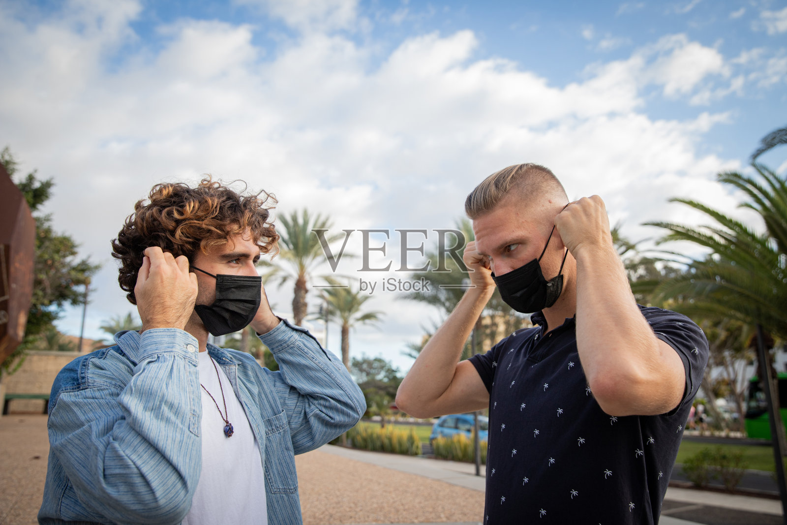 外面的两名男孩戴着医用口罩，以在Covid-19大流行期间保护自己。冠状病毒大流行期间在室外使用口罩的概念照片摄影图片