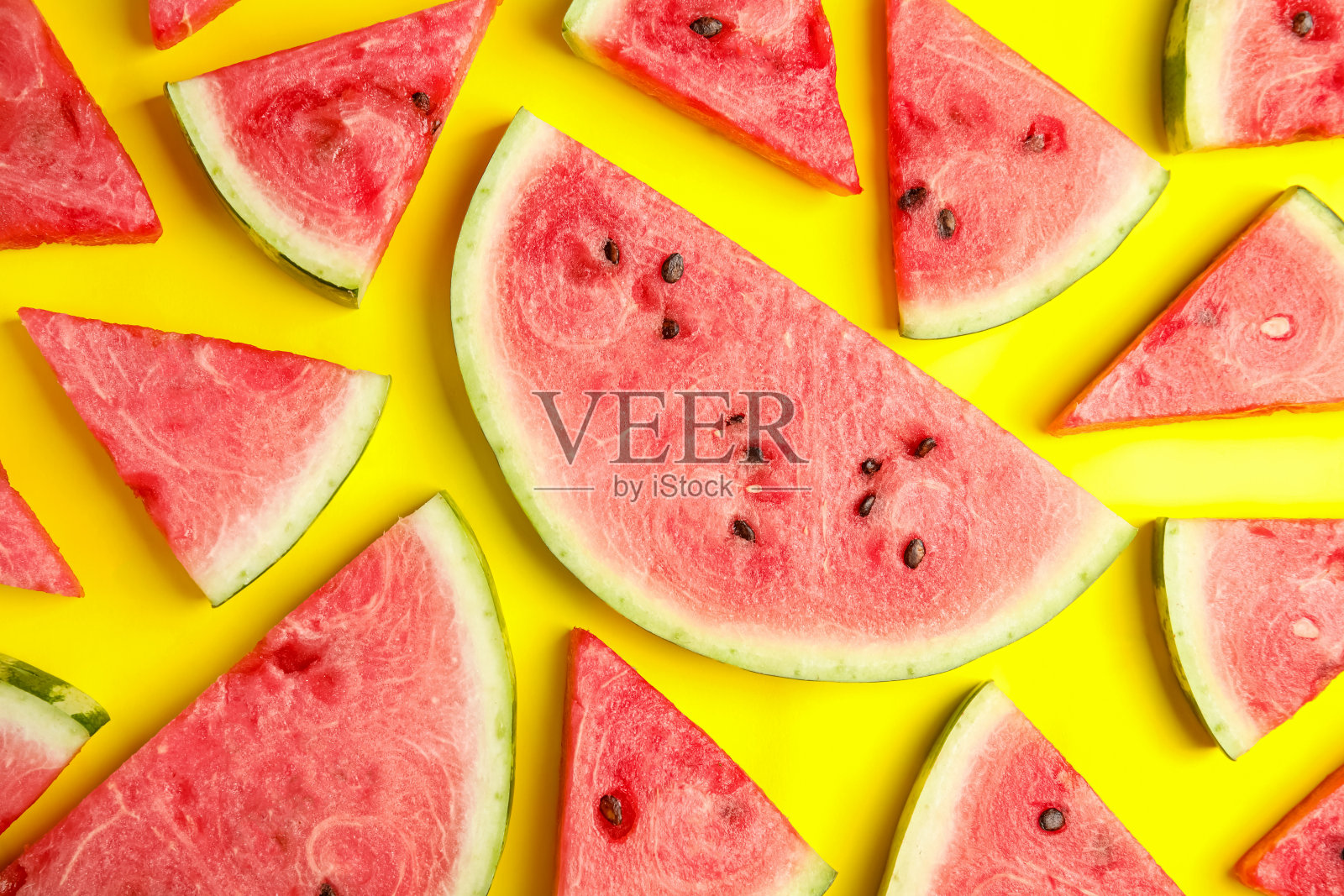 熟透的西瓜片放在黄色的背景上，平放照片摄影图片