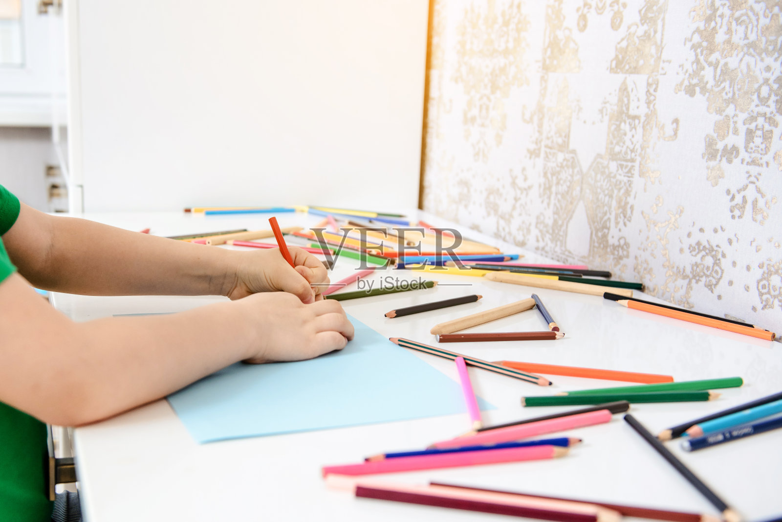 一个在蓝色纸上画画的男孩的侧面图照片摄影图片