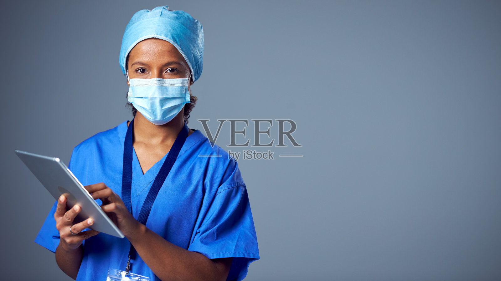 女外科医生使用数码平板电脑穿着手术服和面罩的工作室肖像照片摄影图片