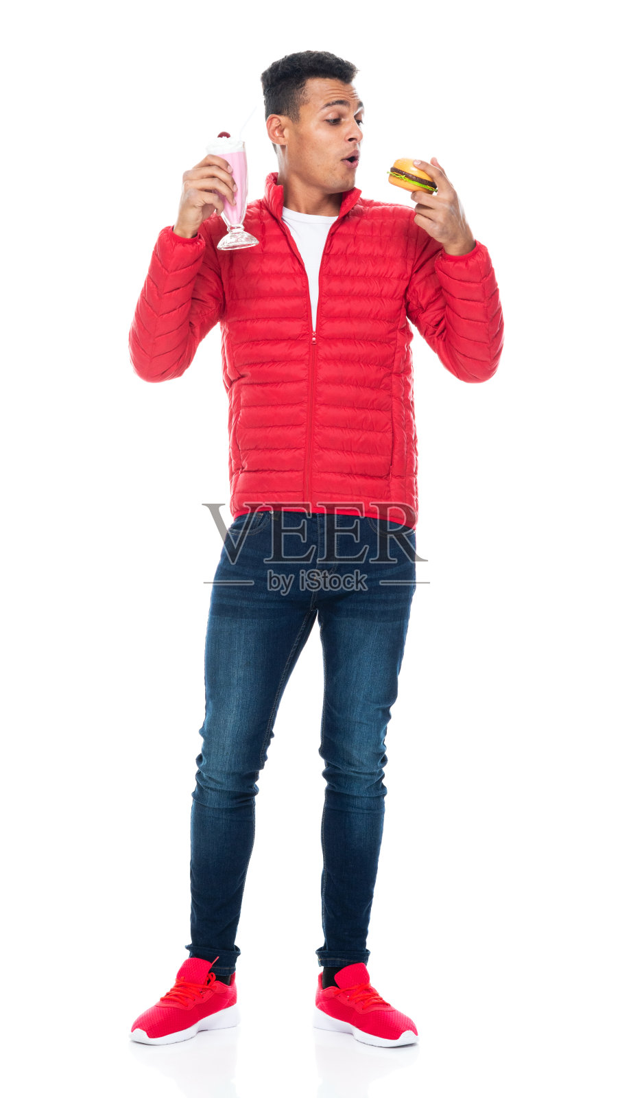 非洲裔男性，穿着帆布鞋，拿着芝士汉堡站在白色背景前照片摄影图片