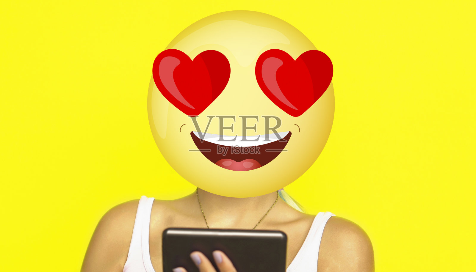 这是社交关系、交友、打字和网上聊天的概念。有一个脸上带着巨大微笑的表情符号，拿着手机，看着里面写满了文字。照片摄影图片