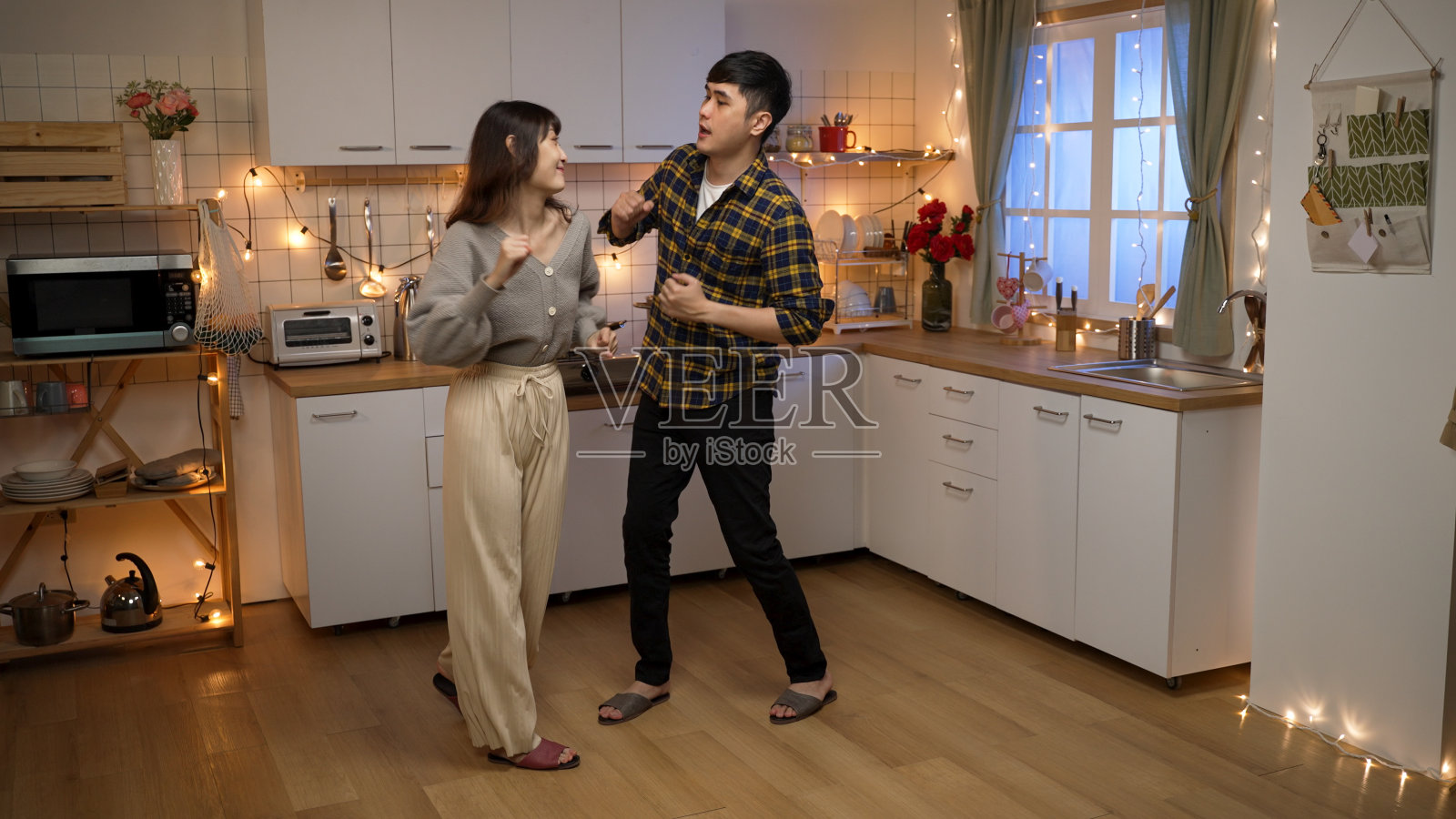 亚洲丈夫和妻子在家里跳舞庆祝情人节的夜晚约会在厨房浪漫的灯光装饰照片摄影图片