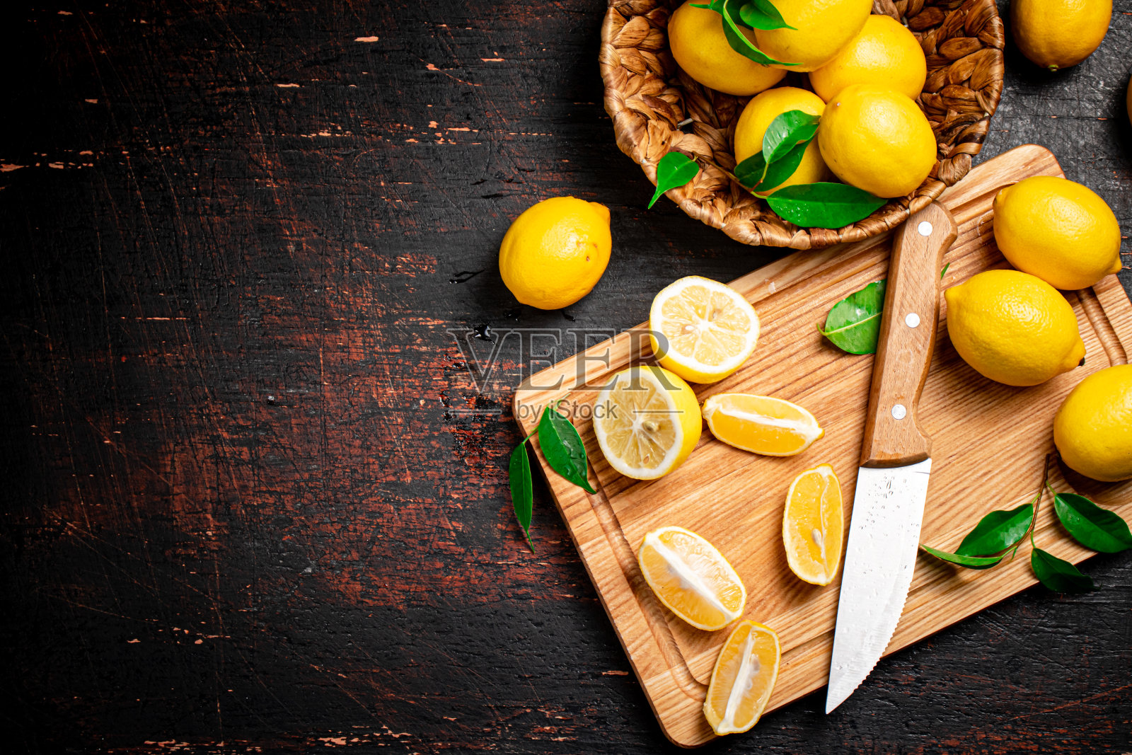 用刀将柠檬切成片放在砧板上，切好叶子。照片摄影图片