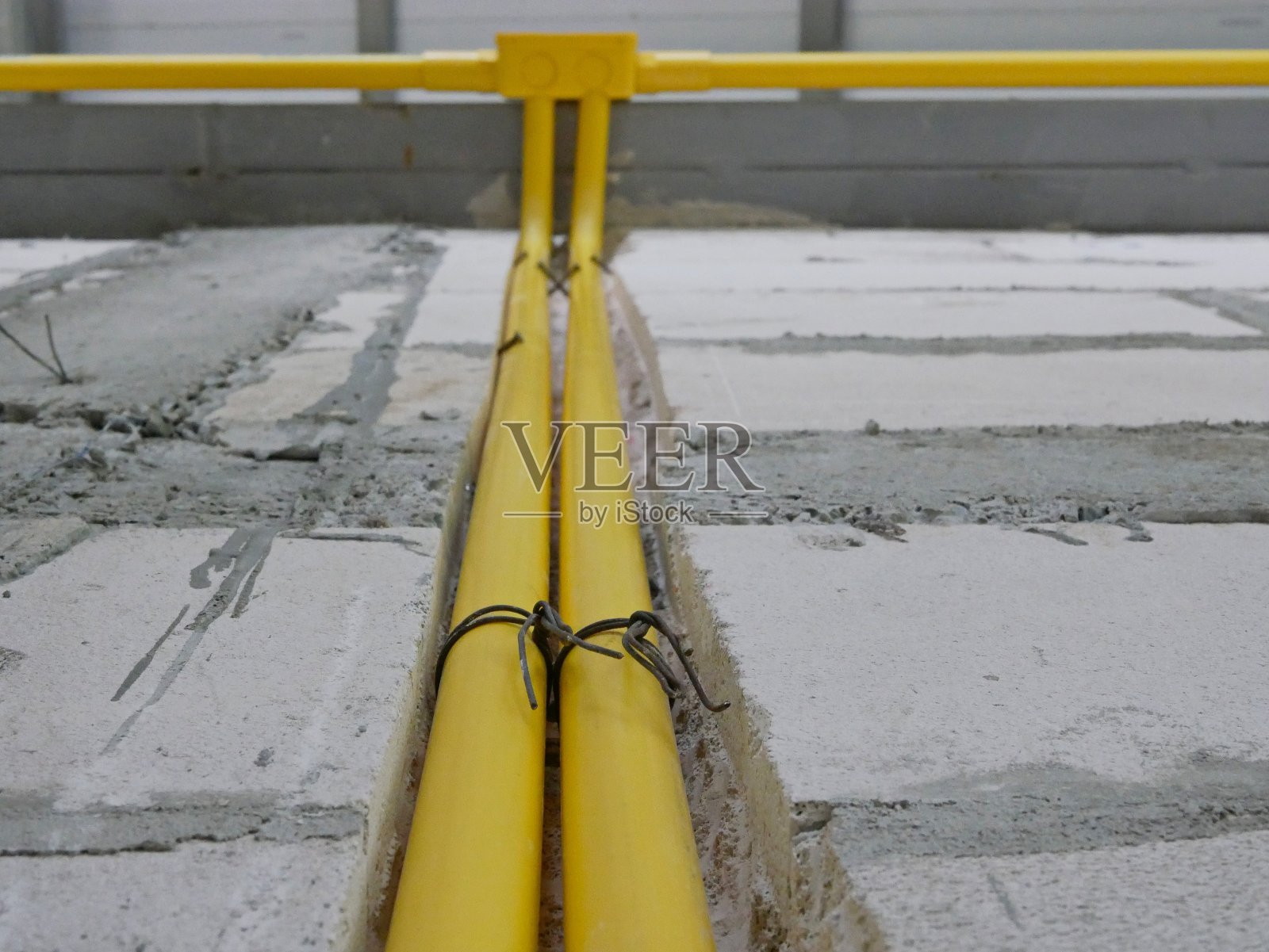 黄色的聚氯乙烯电线管或管道安装在房屋墙壁内或墙壁上方，用于供电和照明照片摄影图片