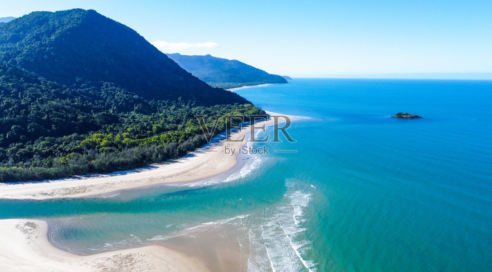 热带雨林覆盖的山脉一直延伸到珊瑚礁边的沙滩上照片摄影图片
