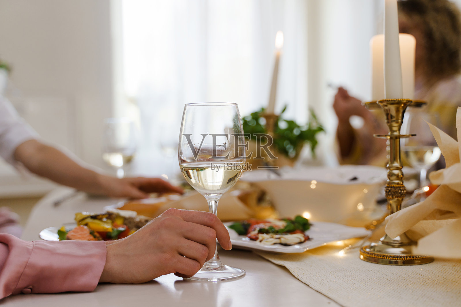 餐桌上拿着酒杯的女人。照片摄影图片