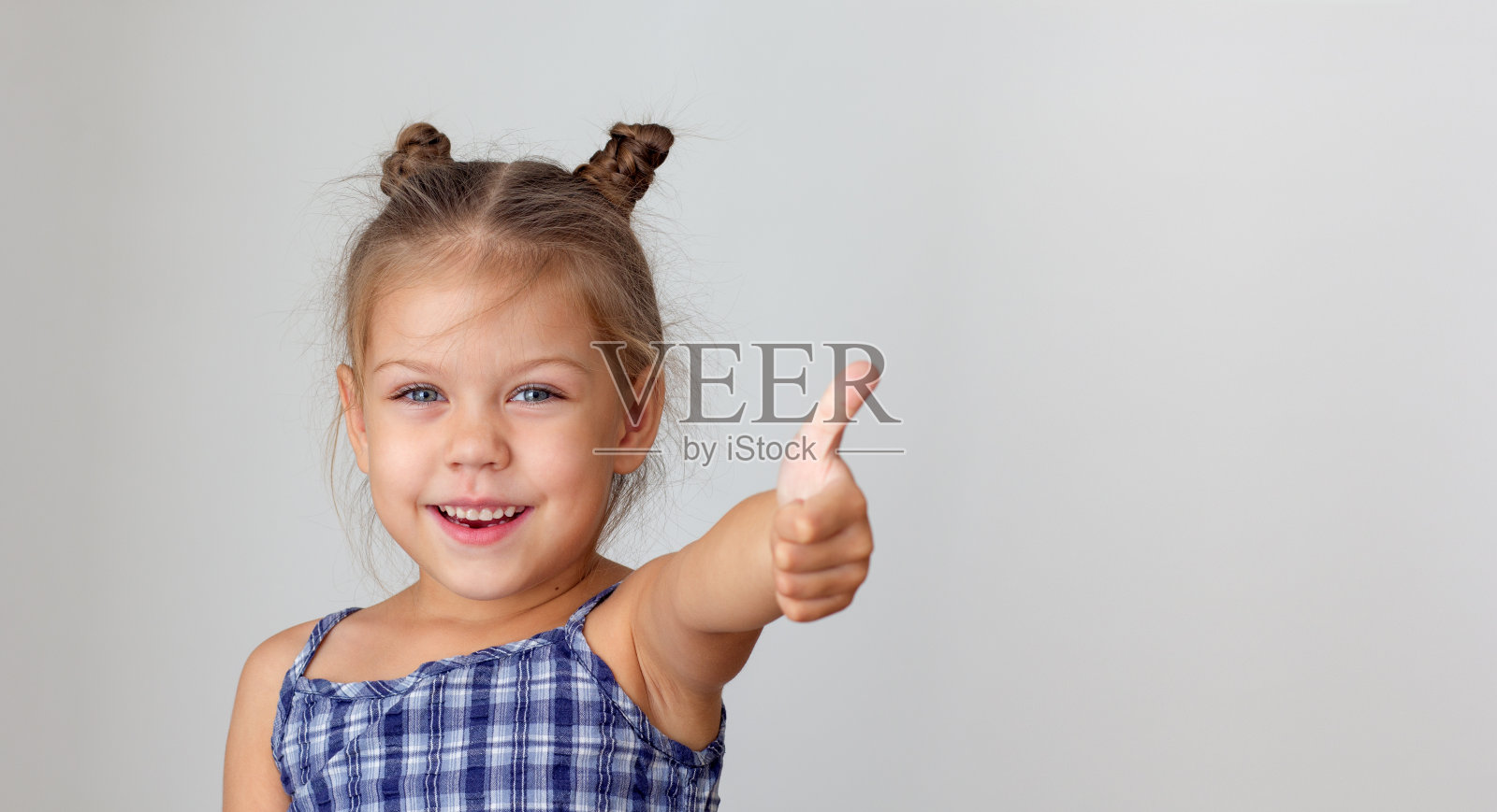 美丽的白人小女孩，孩子，5岁的孩子显示大拇指在灰色背景与复制空间照片摄影图片