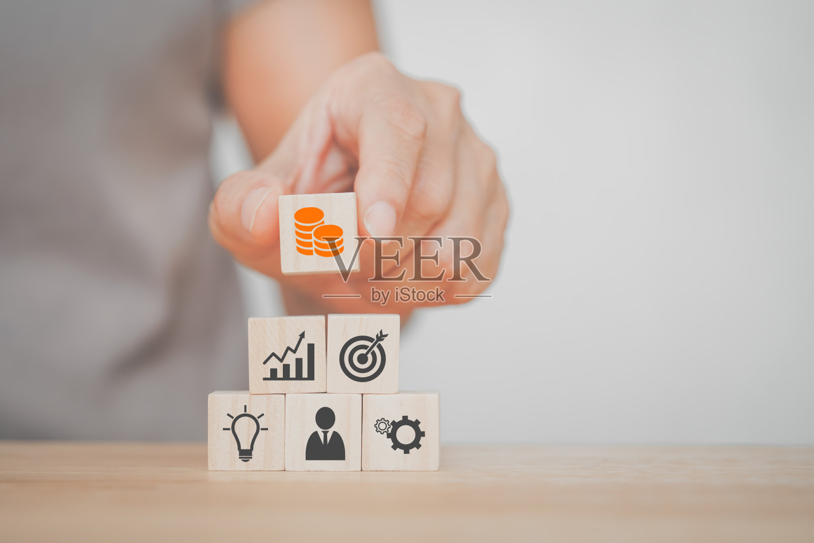 手握木块与橙色的硬币图标放在金字塔的顶部为商业和金融的概念照片摄影图片