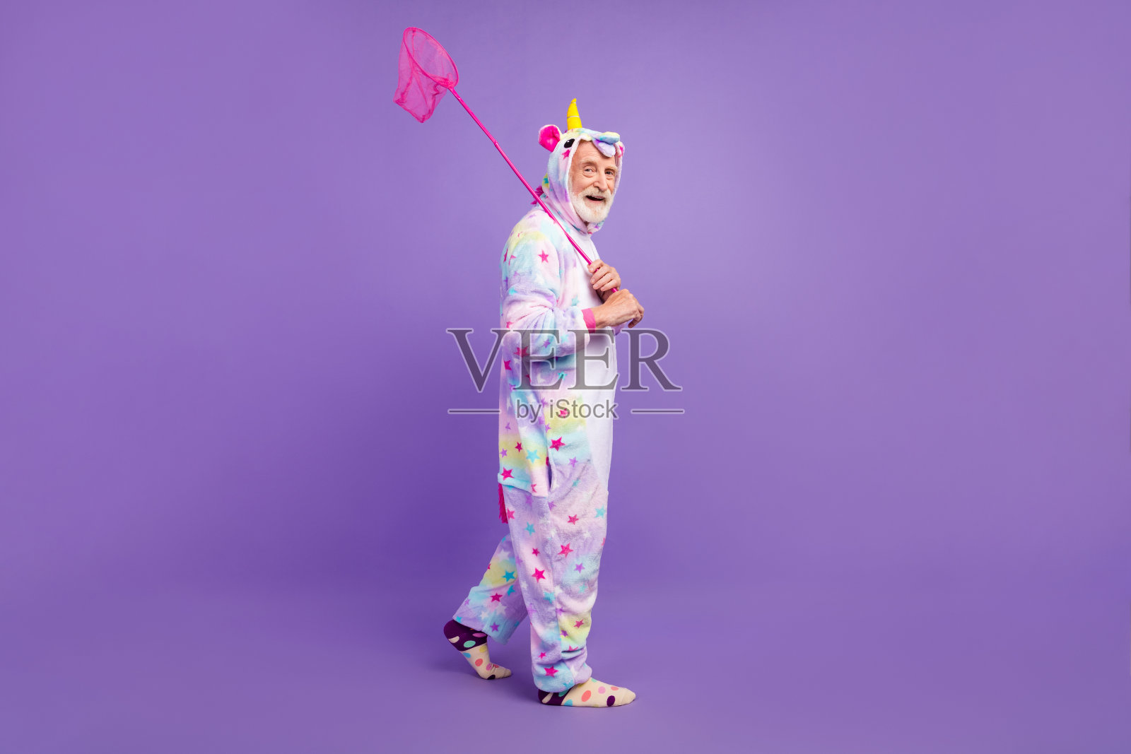 迷人的有趣的男人养老金独角兽睡衣的照片散步捕捉蝴蝶微笑孤立的紫罗兰色背景照片摄影图片