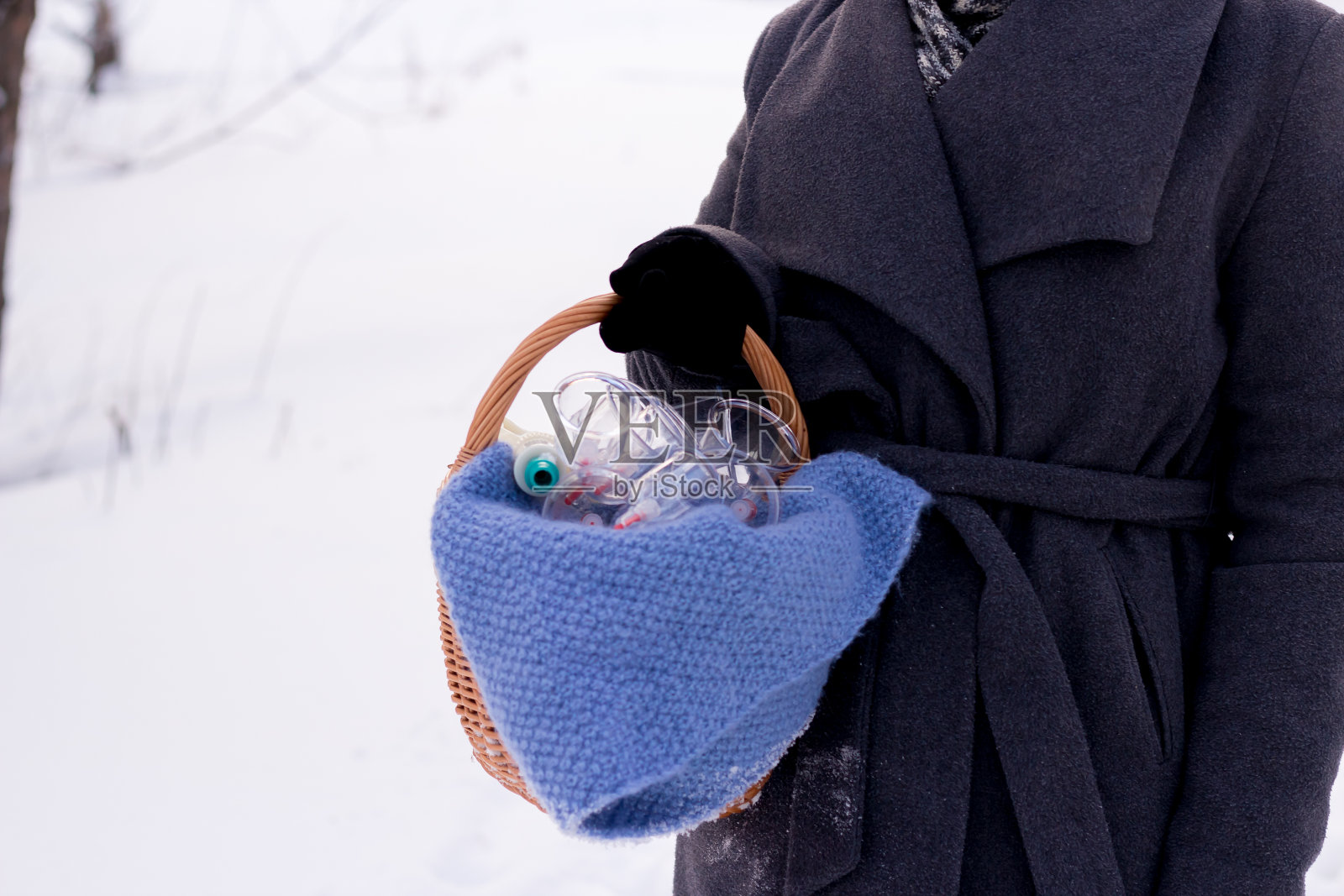 一位身穿灰色外套的妇女，手里拿着一篮子海马罐头。海马瓶，海马泵，放血，中药照片摄影图片