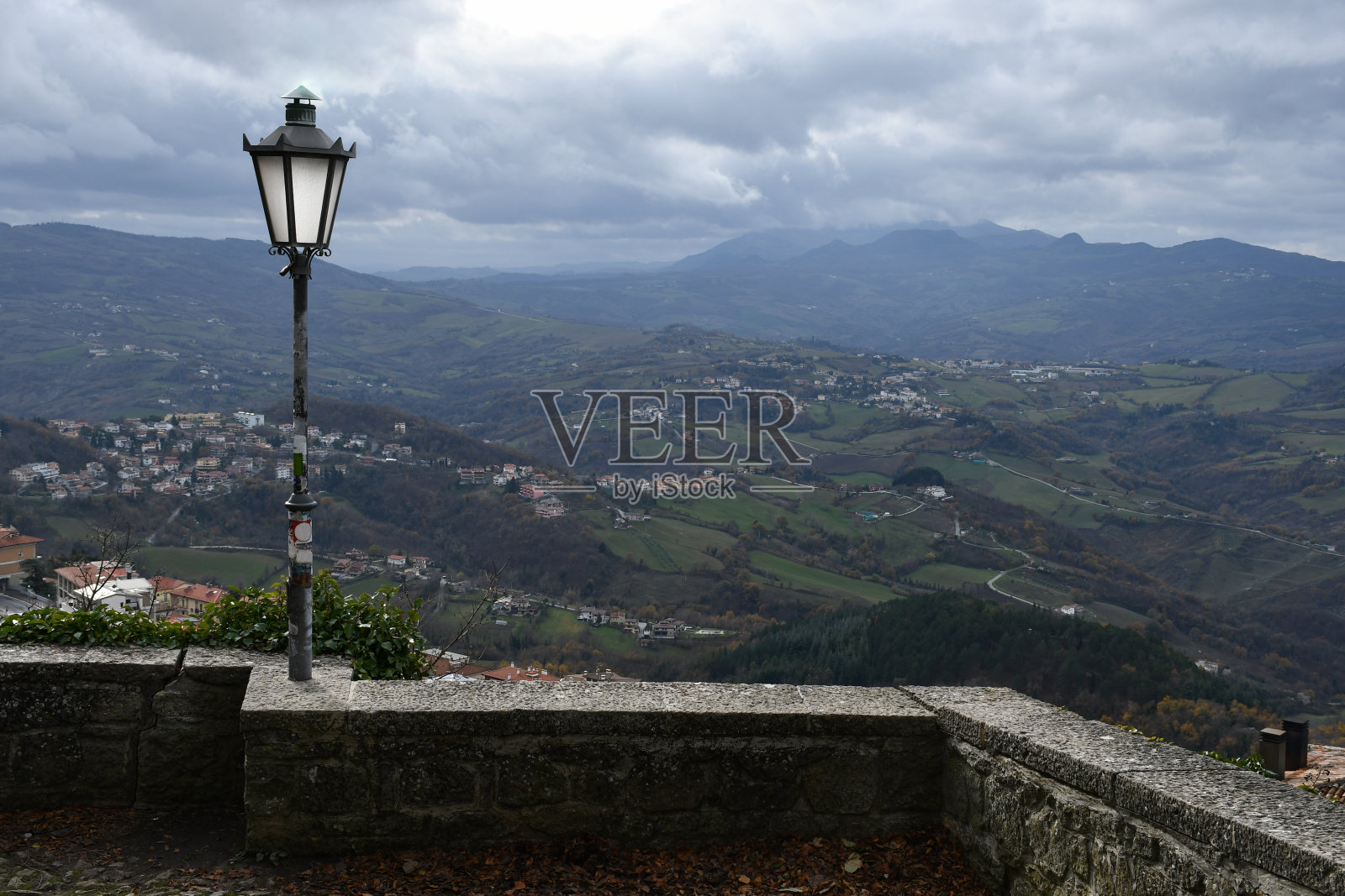 圣马力诺山区背景下墙上的路灯照片摄影图片