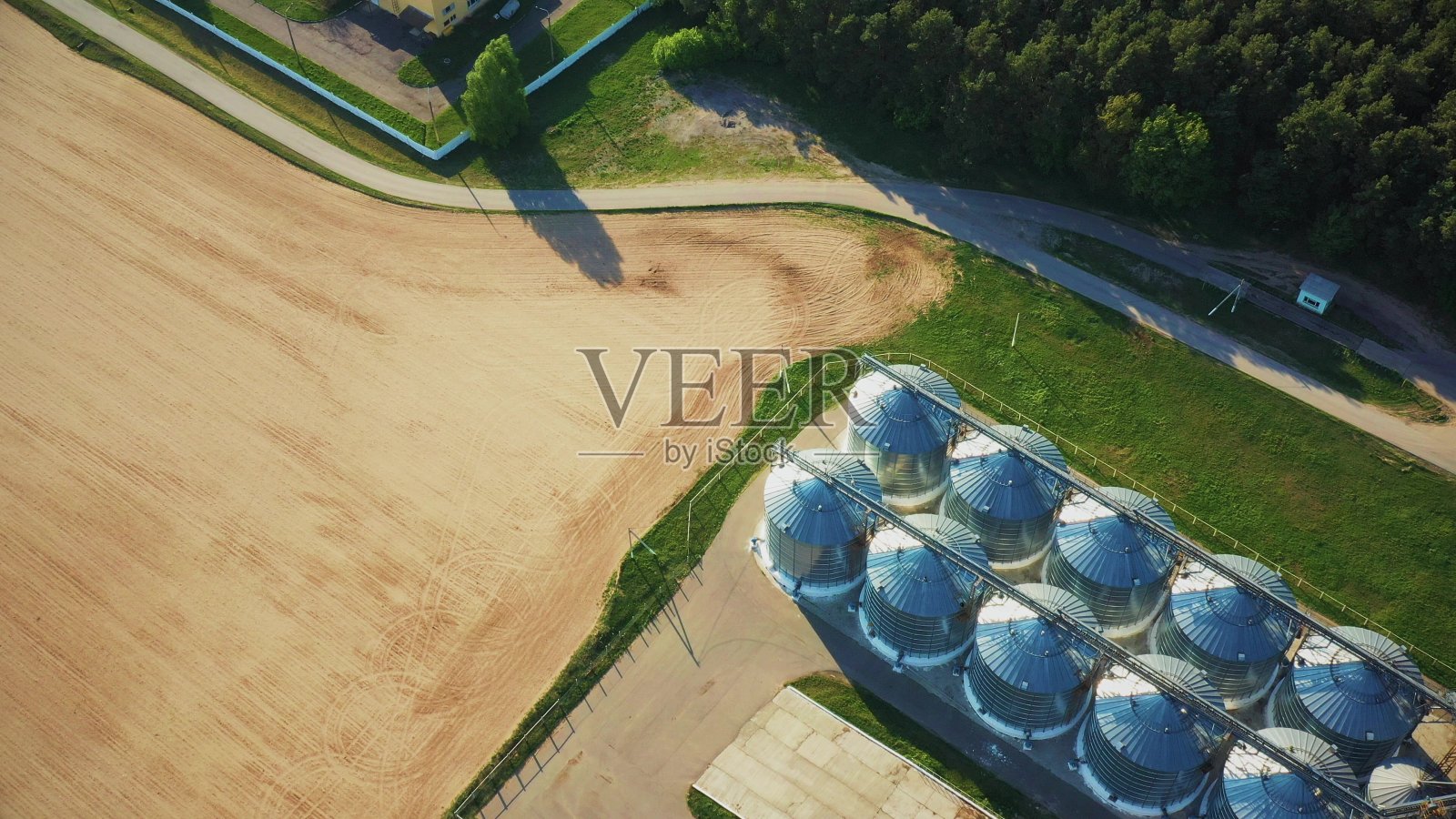 4K架空顶视图现代粮仓，谷物干燥综合体，商业谷物或种子筒仓在阳光明媚的春天乡村景观。采购产品玉米烘干机筒仓，内陆谷物码头，田里的谷物升降机照片摄影图片