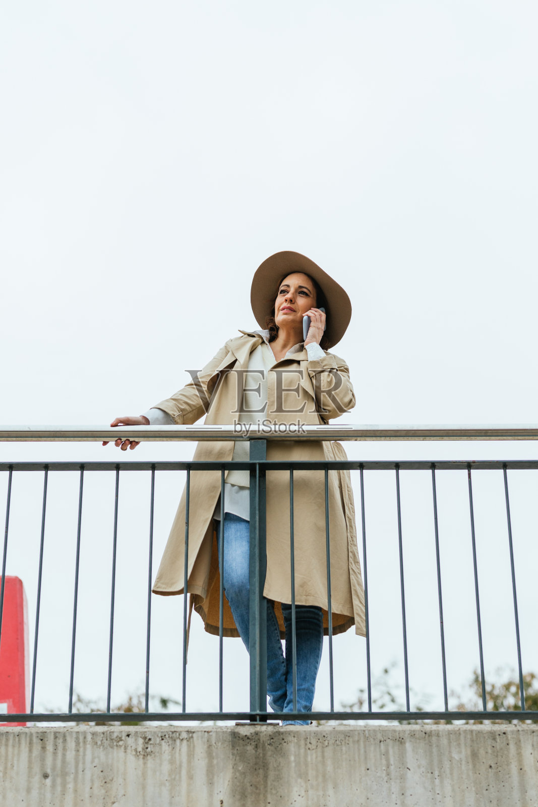 一个成年女人靠在栏杆上打电话照片摄影图片